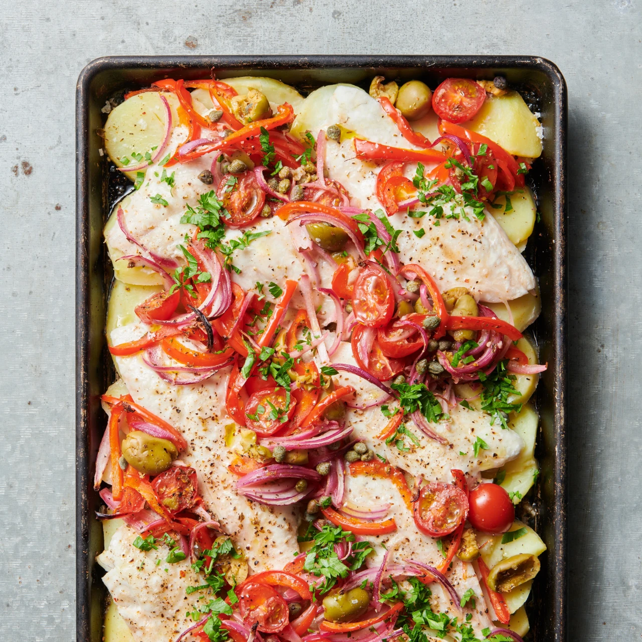 Tray baked fish served with potatoes and mediterranean vegetables. Use snapper, gurnard or hoki fish for this recipe. 