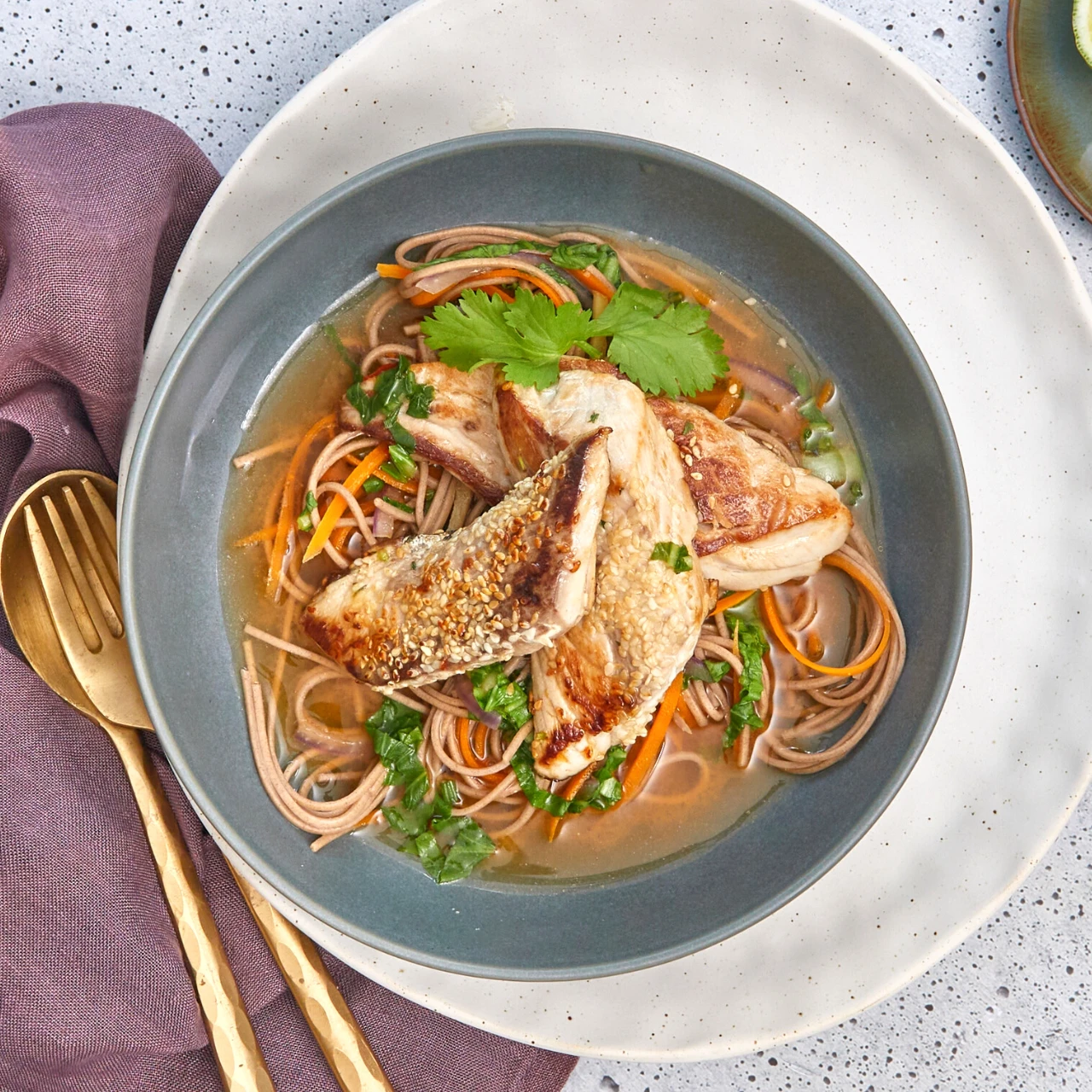 Sesame-crusted kahawai fish in Asian soba noodle soup in a bowl.