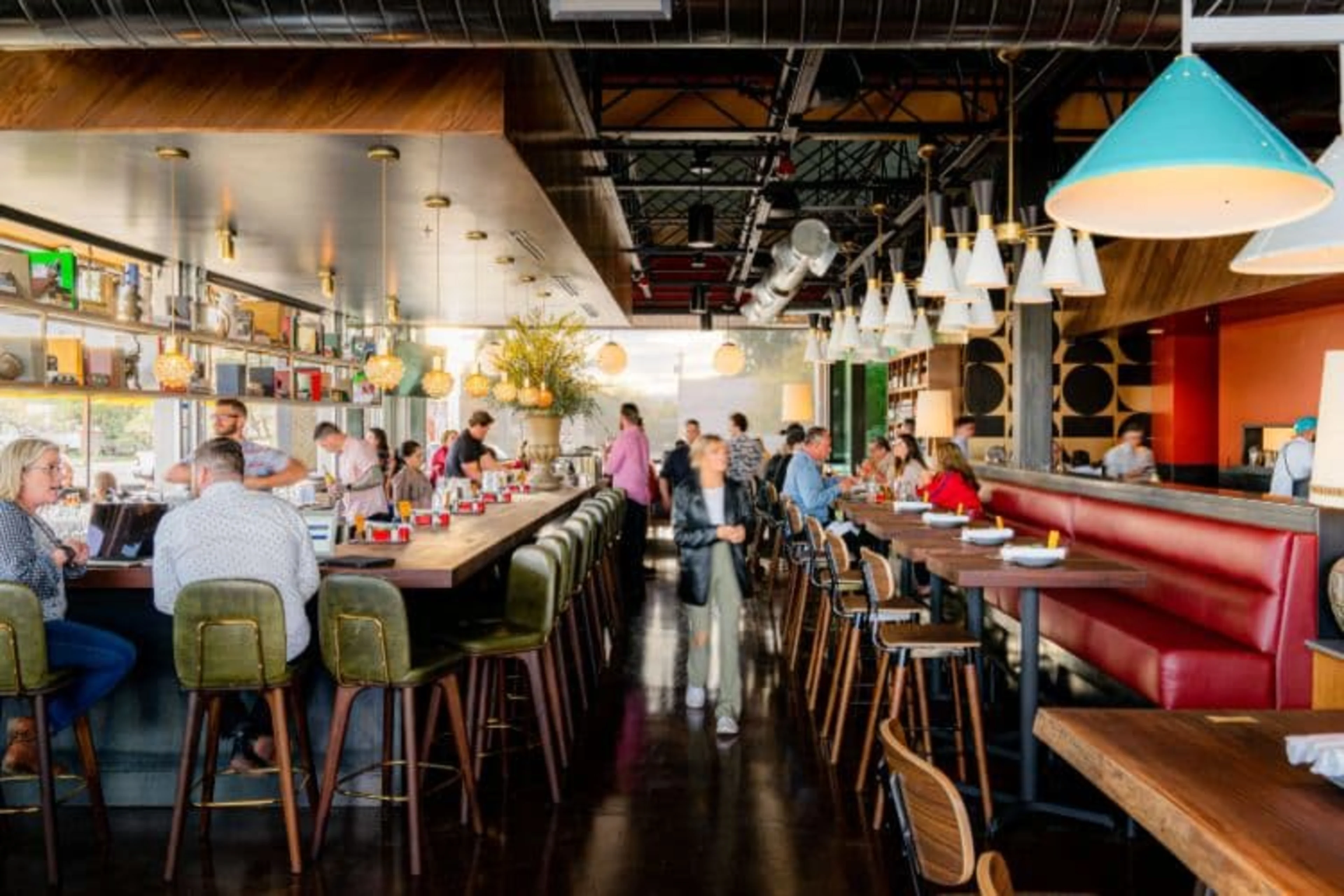 A long bar and a long red bench with tables.