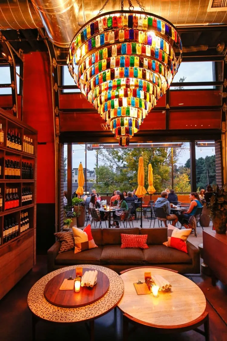 Colorful glass chandelier hangs about restaurant tables.