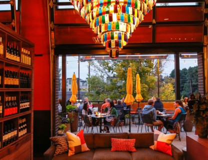 Colorful glass chandelier hangs about restaurant tables.