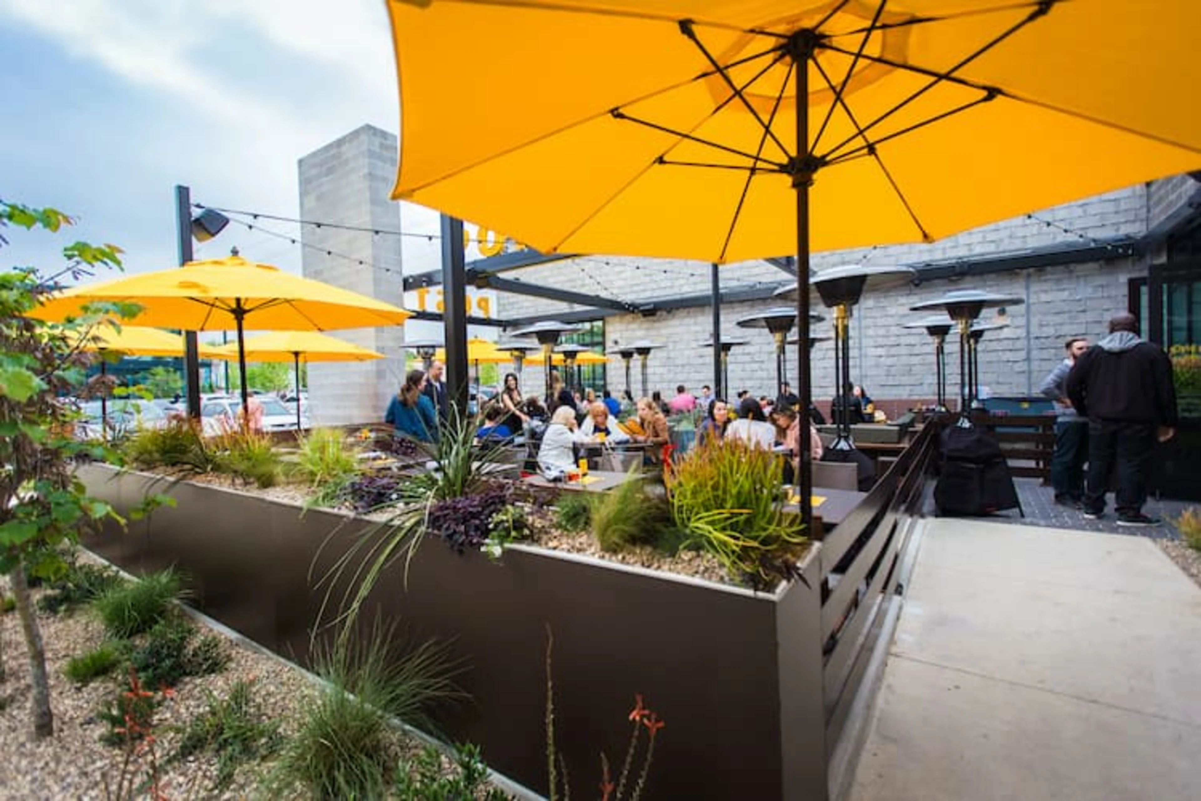 A restaurant patio with customers under yellow umbrellas.