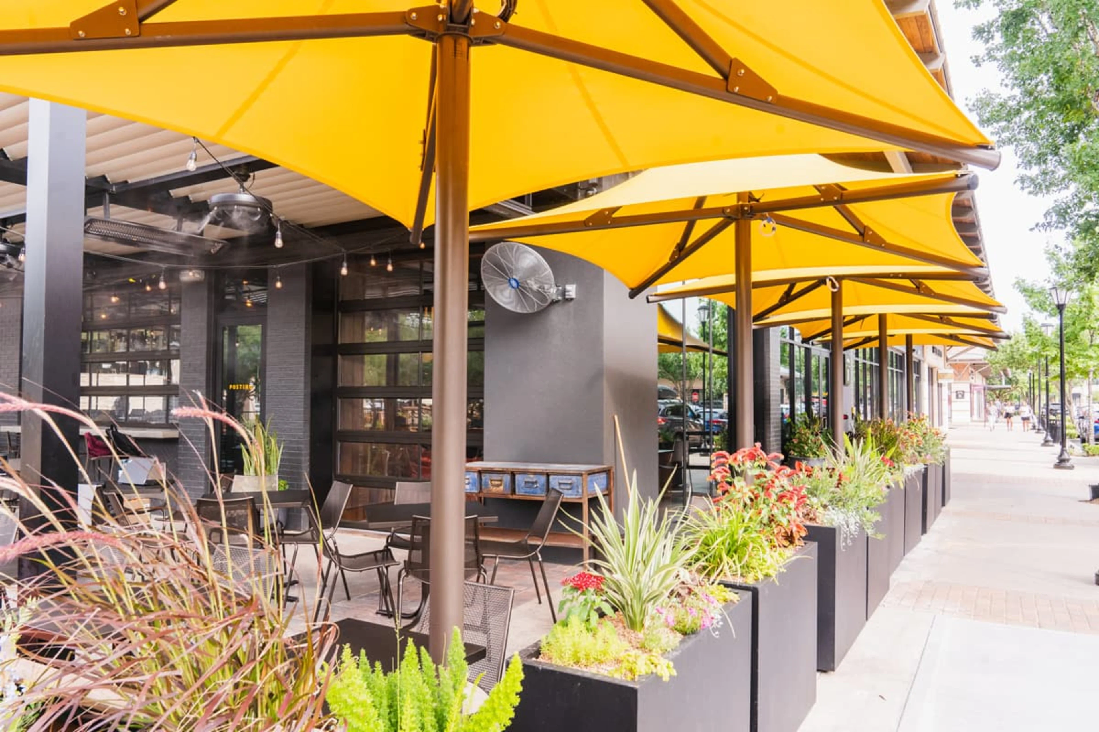 Large yellow umbrellas covering a patio with flower boxes.