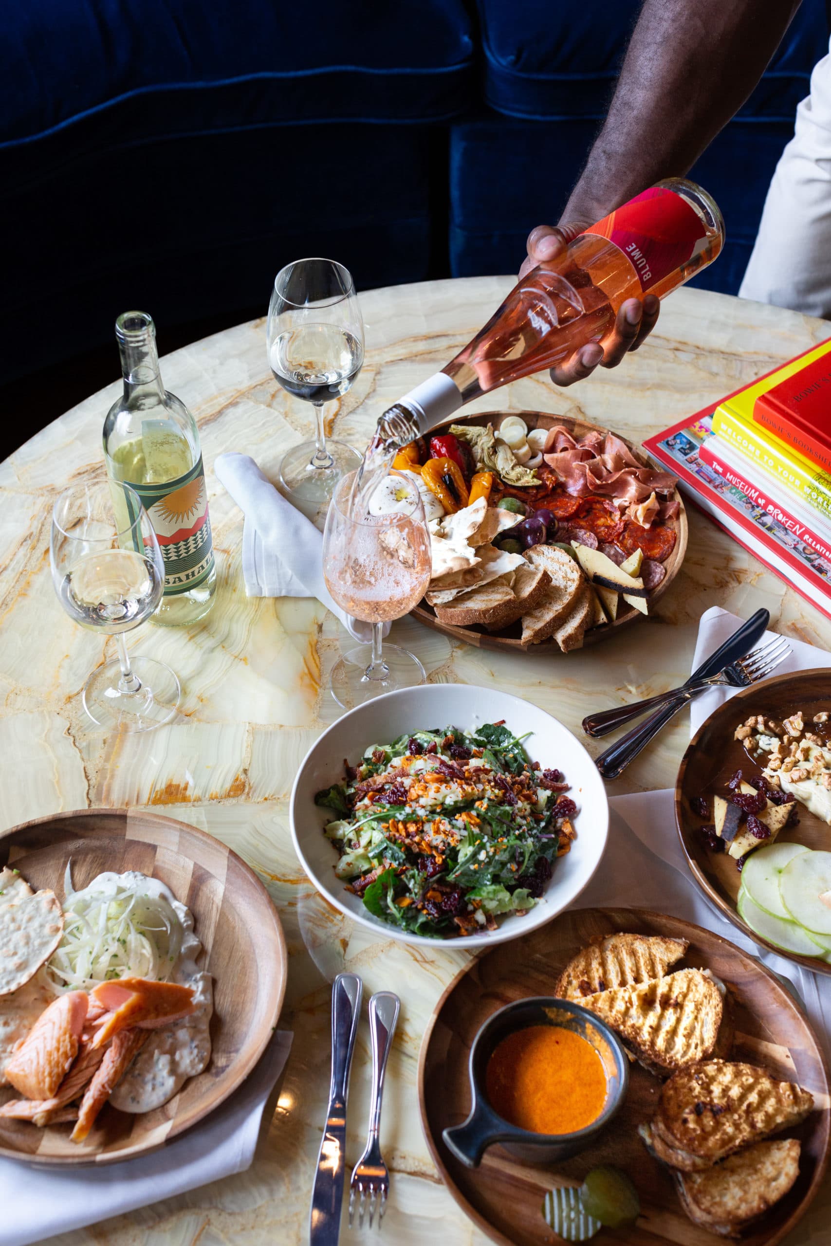 A table full of food and a server pouring rose wine.