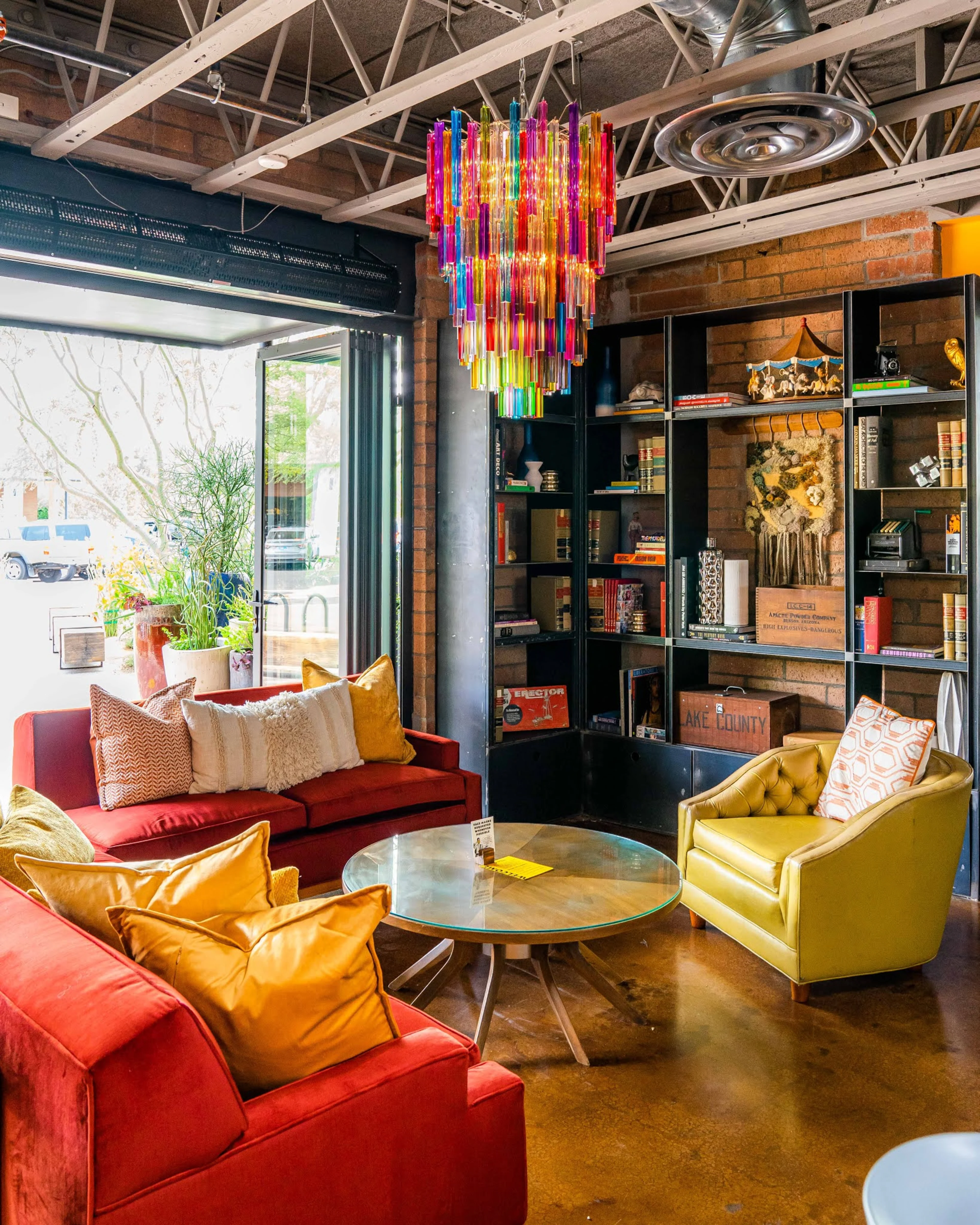 A large empty room with orange couches and a colorful chandelier.