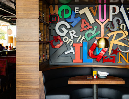 A booth table with large colorful letters on the wall behind it.