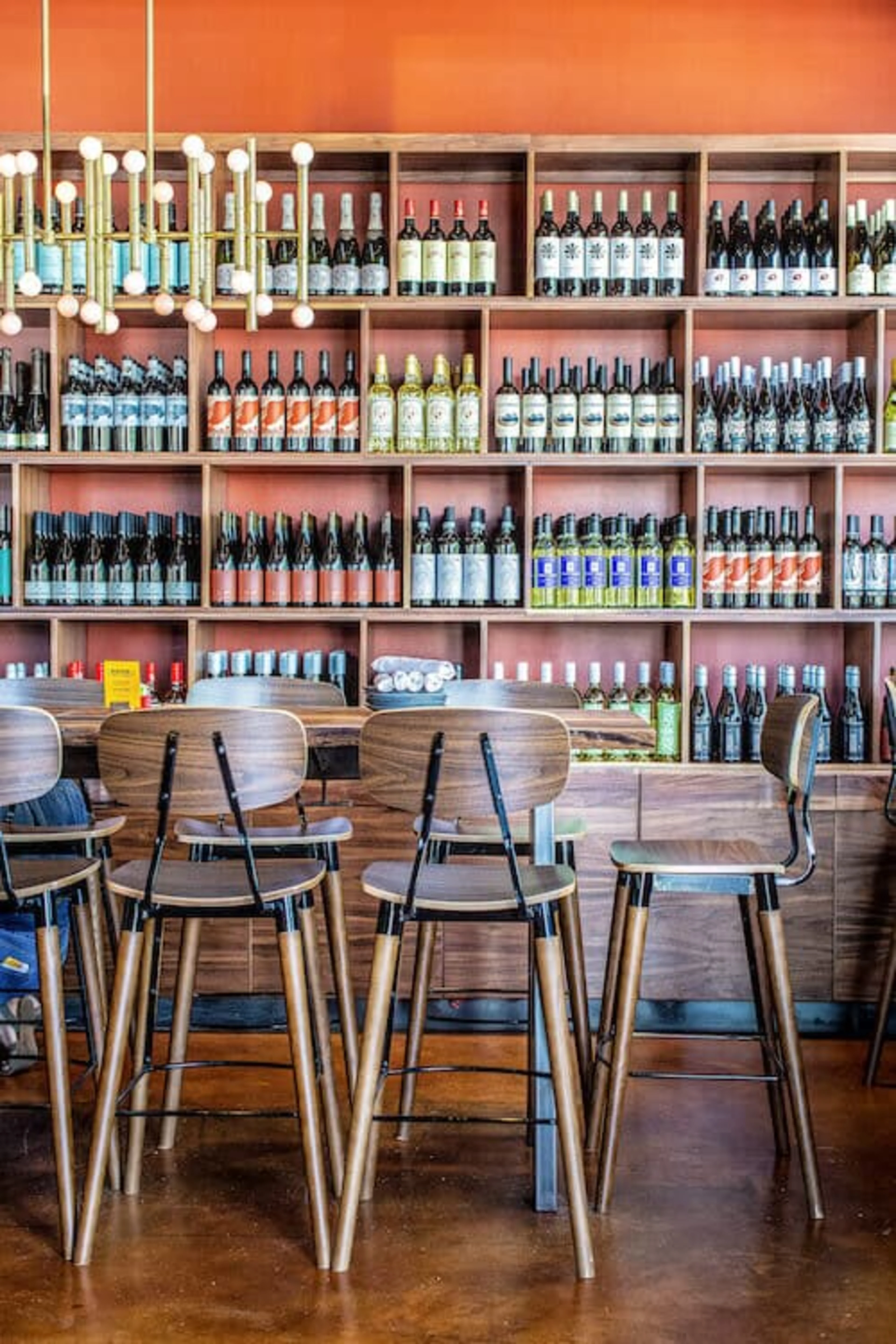 A long wooden table with a wall of wine behind it