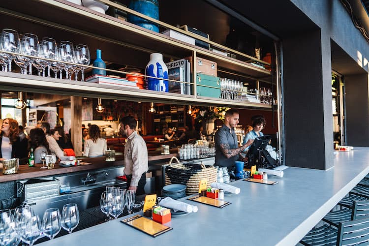 A busy restaurant bar with two bartenders working.