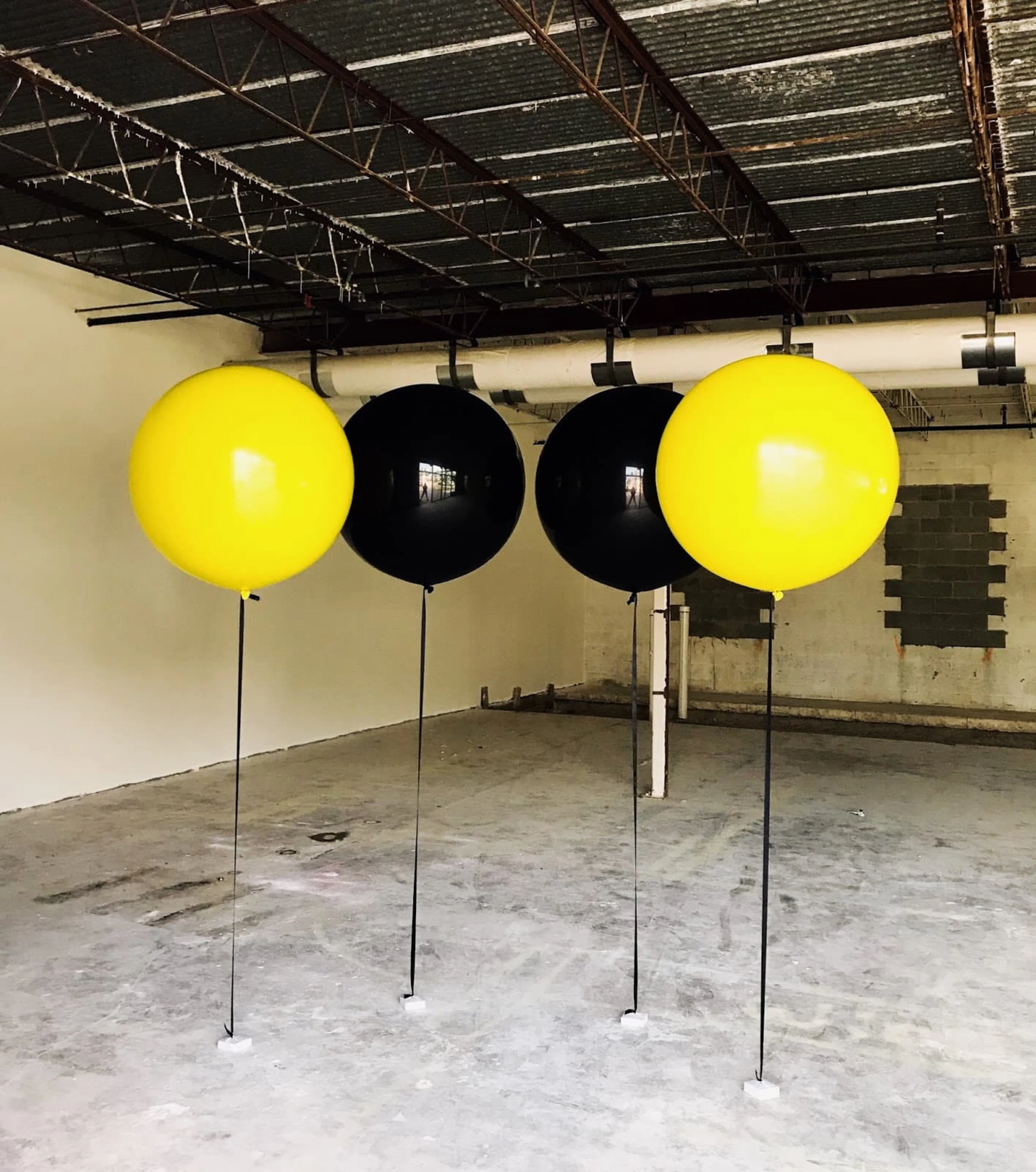Black and yellow balloon in an empty concrete room.