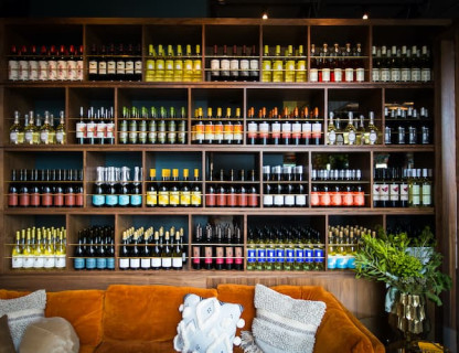 A large wine display on shelves above an orange couch.