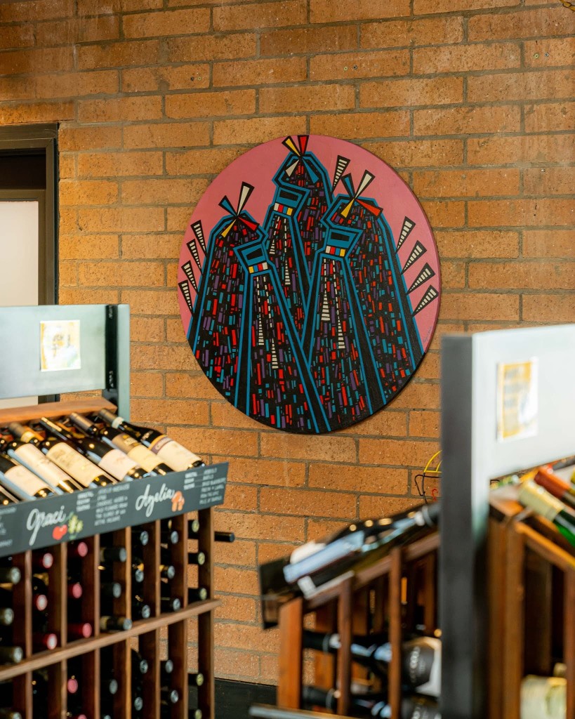 A brick wall with art and wine racks in front of it