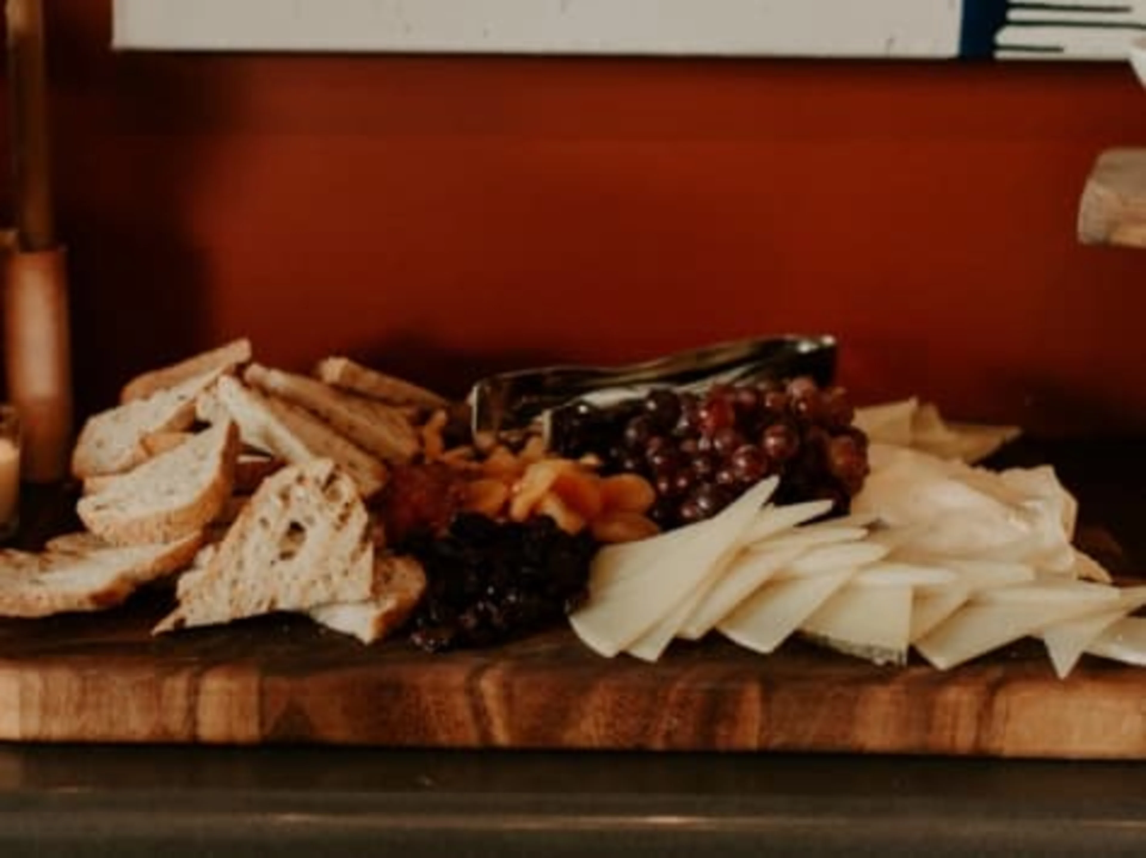A wooden board covered in bread, cheese and fruits.