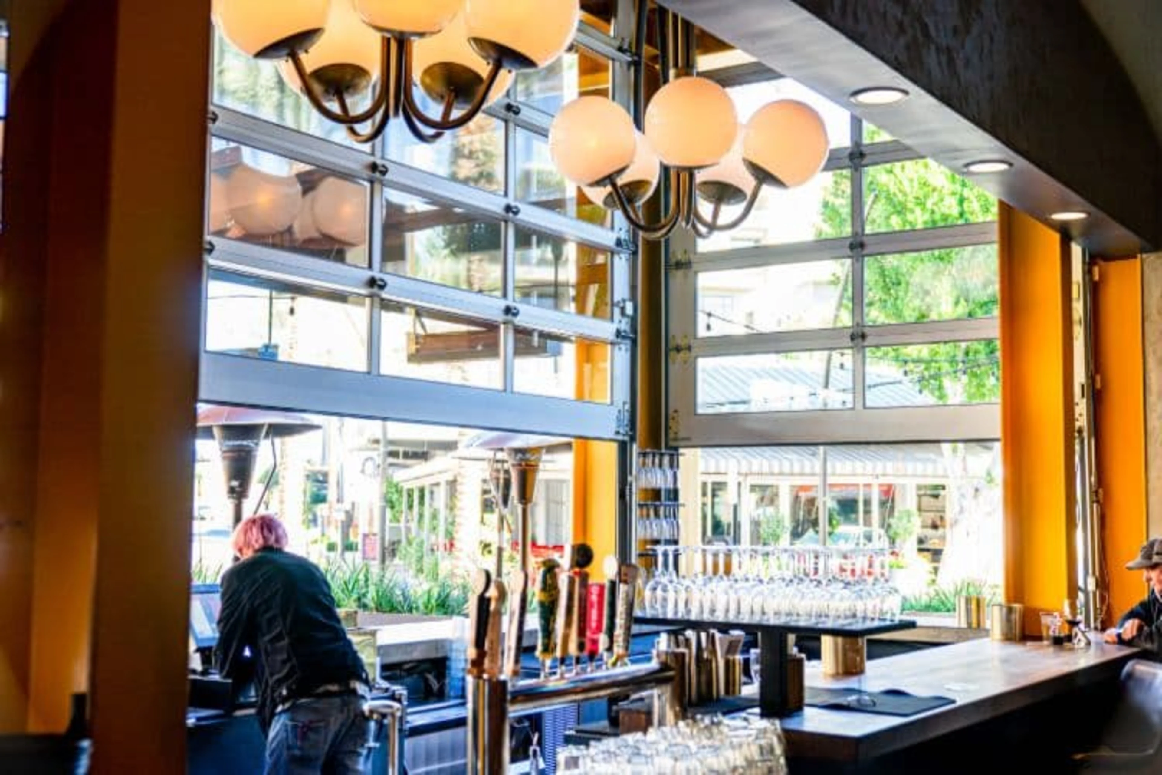 A garage door bar open with a bartender leaning out.