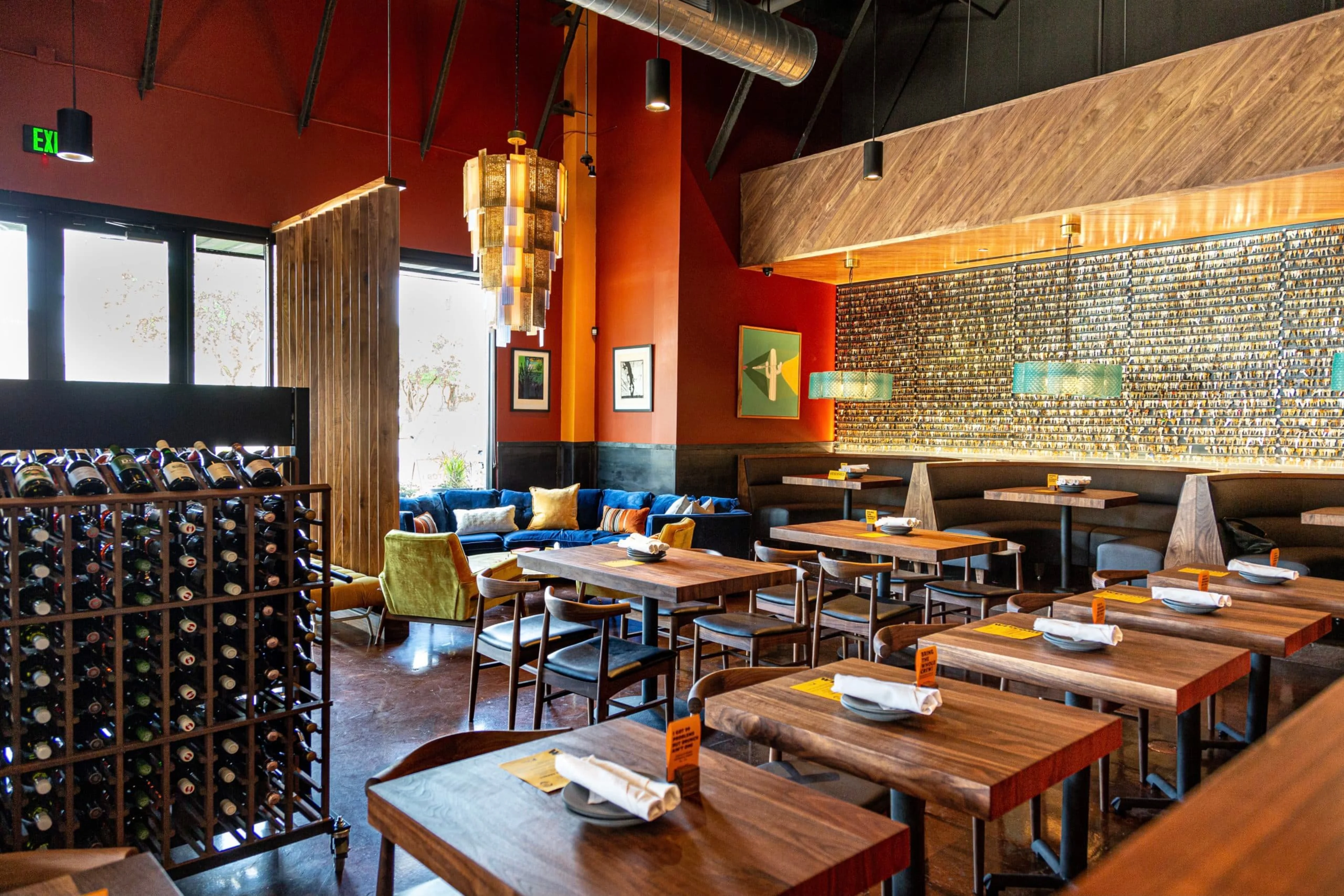 An empty restaurant with rows of tables and a wine rack.