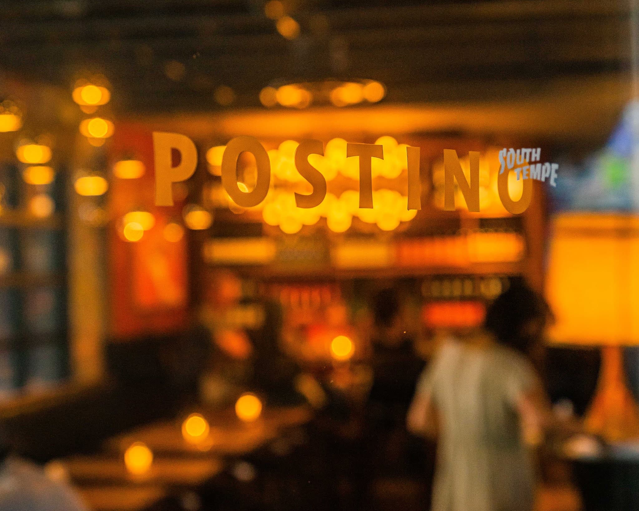 A glass window with Postino South Tempe logo on it