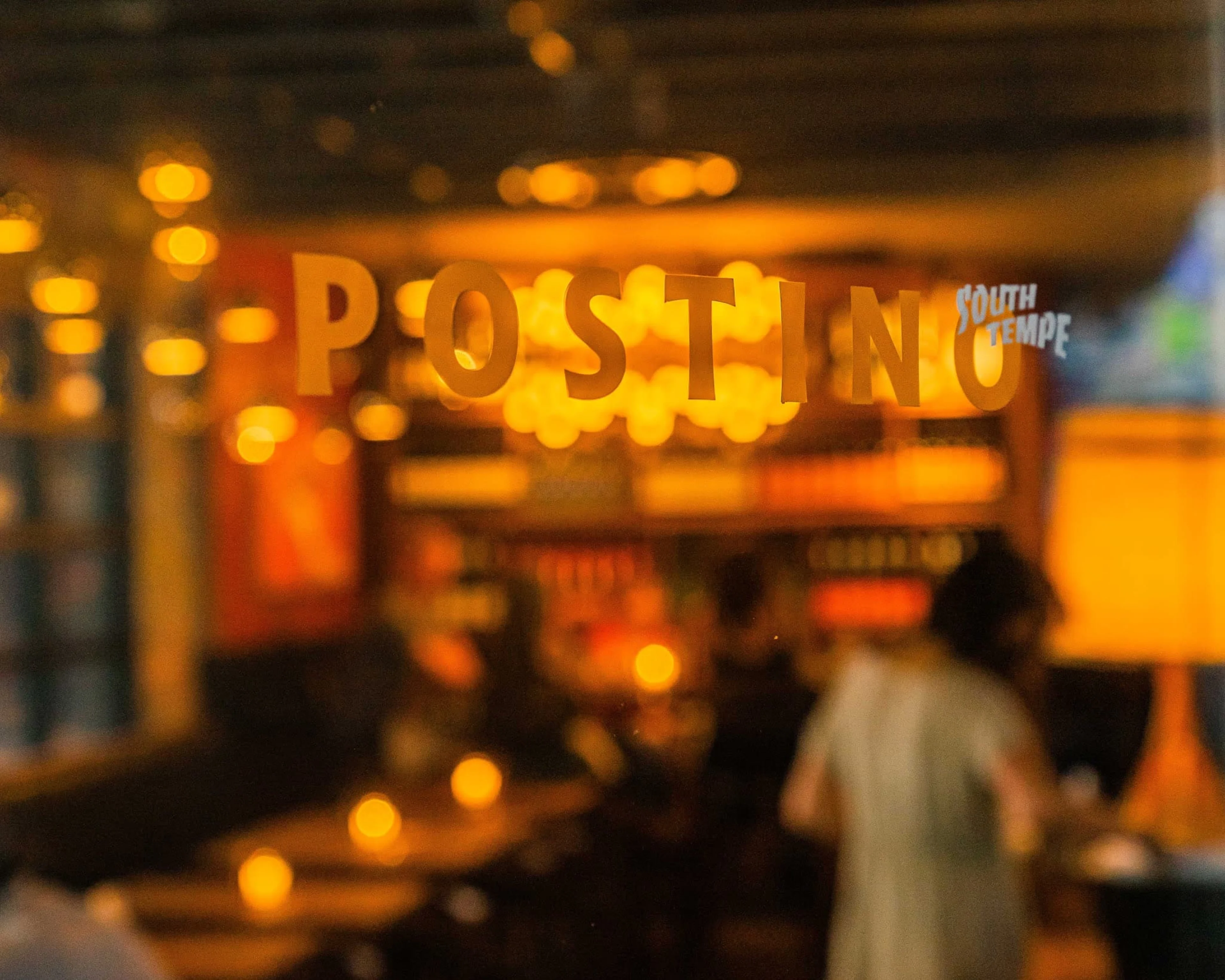 A glass window with Postino South Tempe logo on it