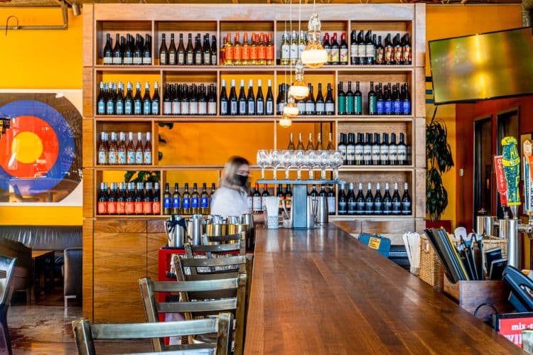 A large wall of wine with yellow walls.