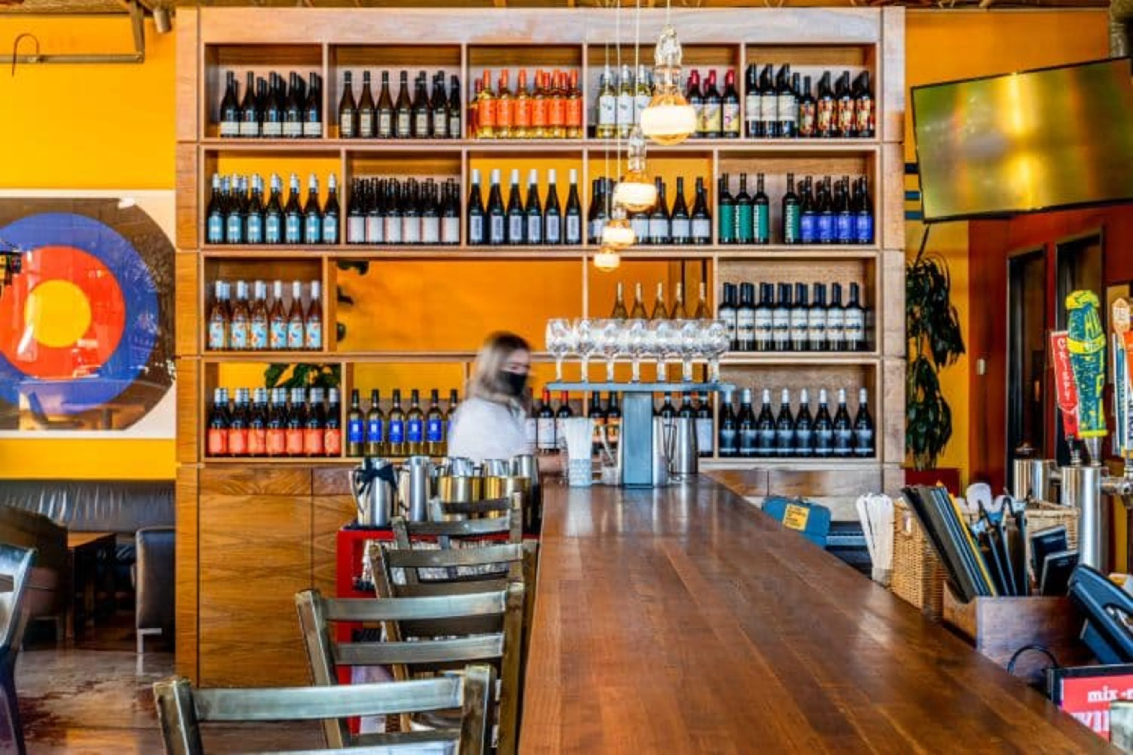 A large wall of wine with yellow walls.