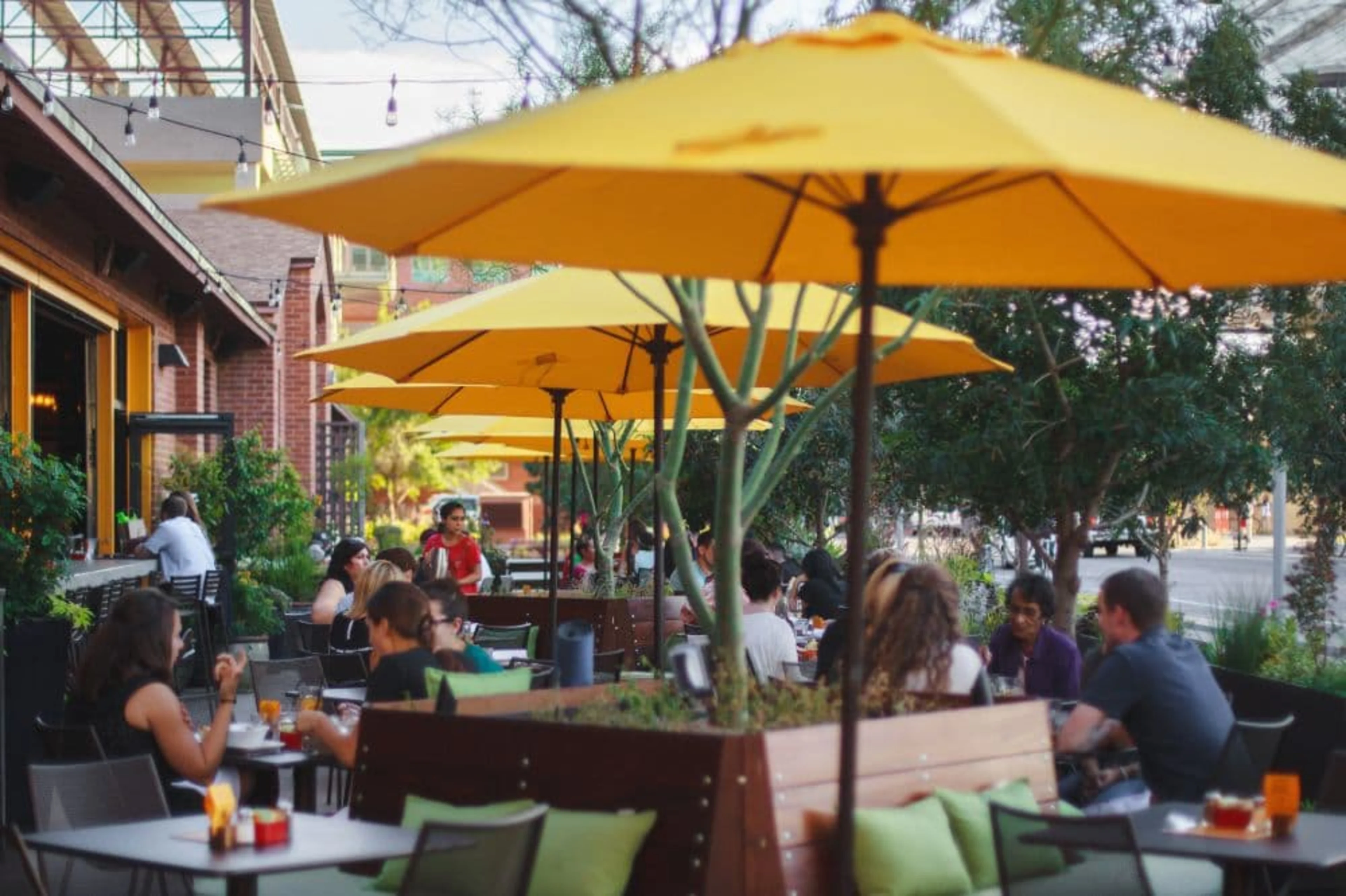 Patio with yellow umbrellas and people dining.