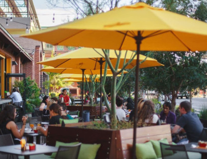 Patio with yellow umbrellas and people dining. 
