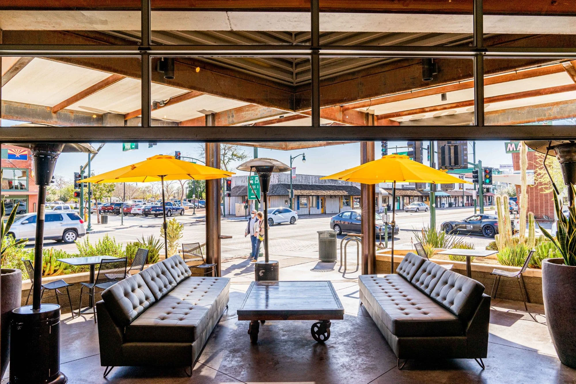 A restaurant patio with leather sofas and yellow umbrellas.