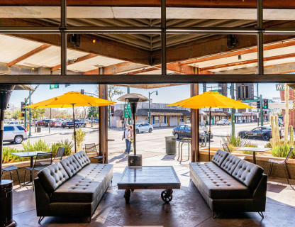 A restaurant patio with leather sofas and yellow umbrellas.