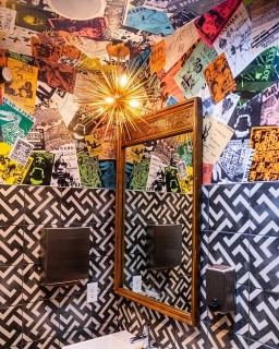 A bath room with half black and white half colorful walls, and a sputnik chandelier. 
