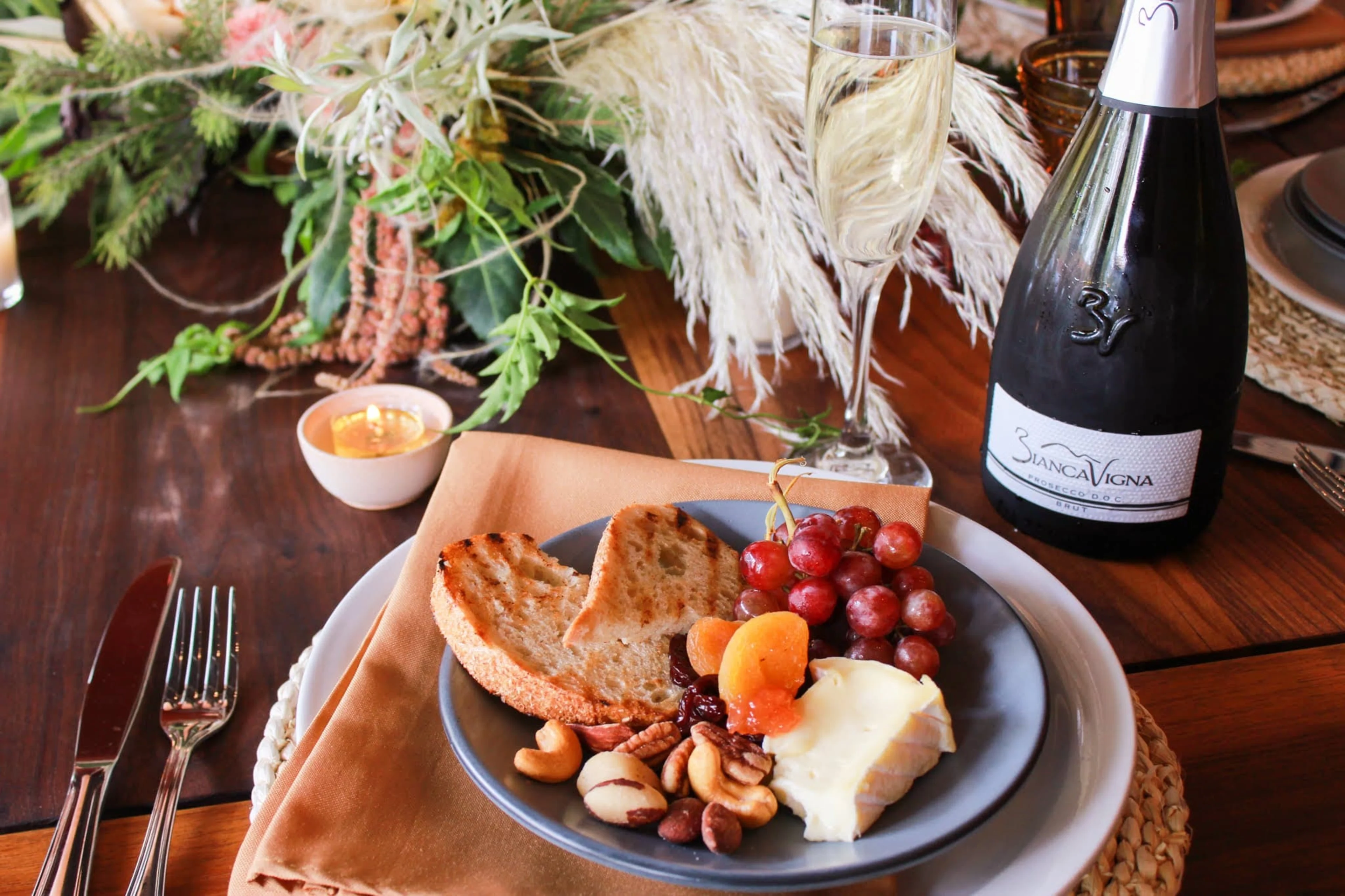 A table setting with a plate full of food and a bottle of wine.