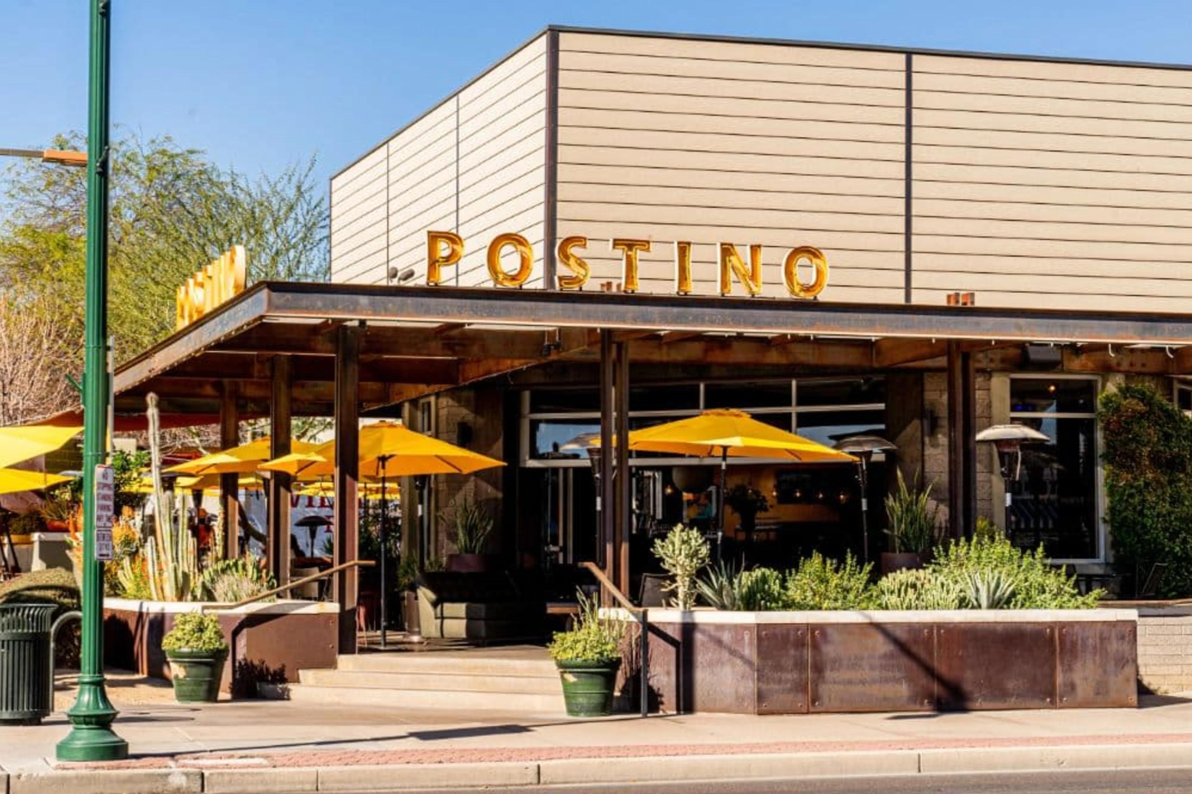 Building with yellow umbrellas and a Postino sign