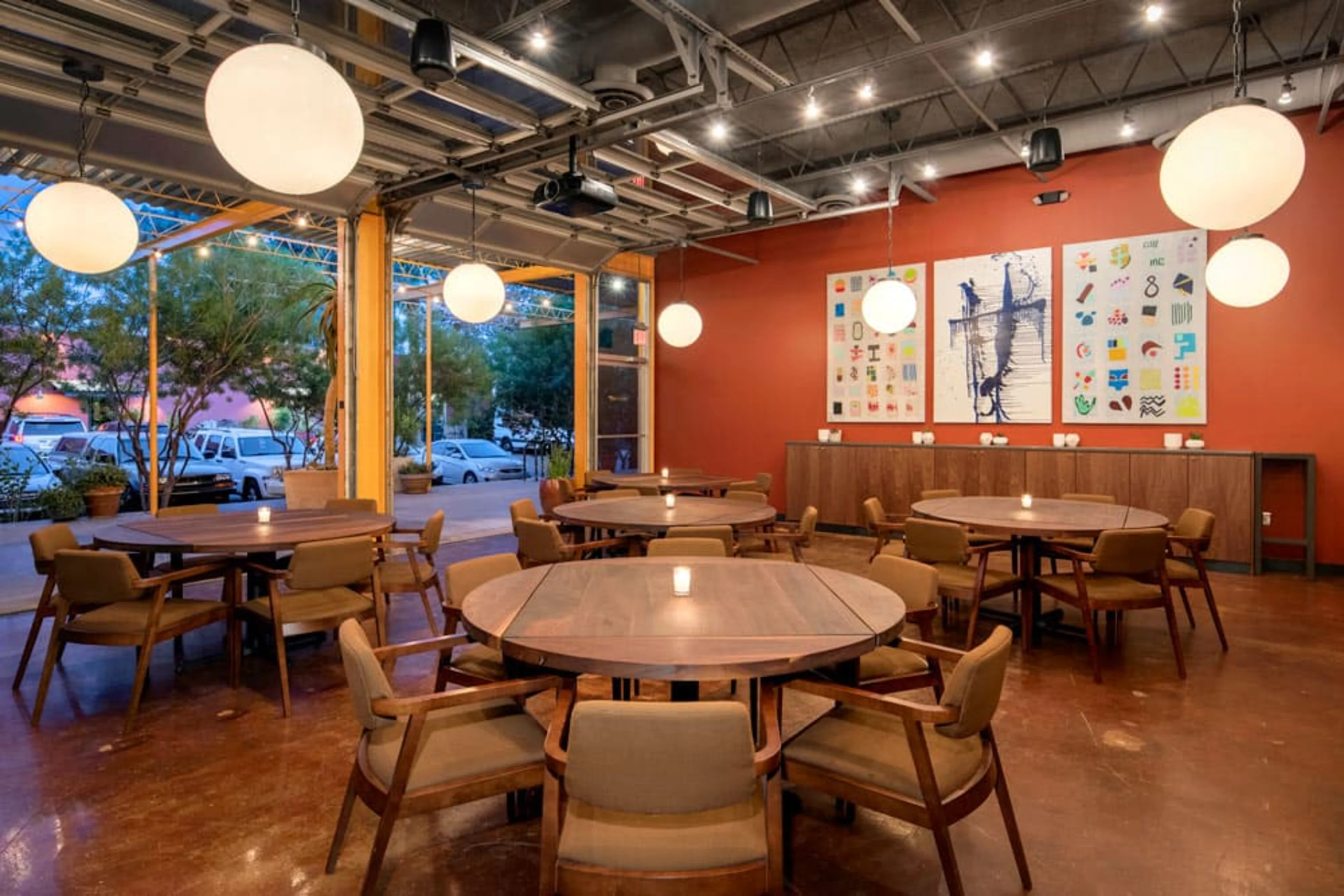 An orange room with round tables.