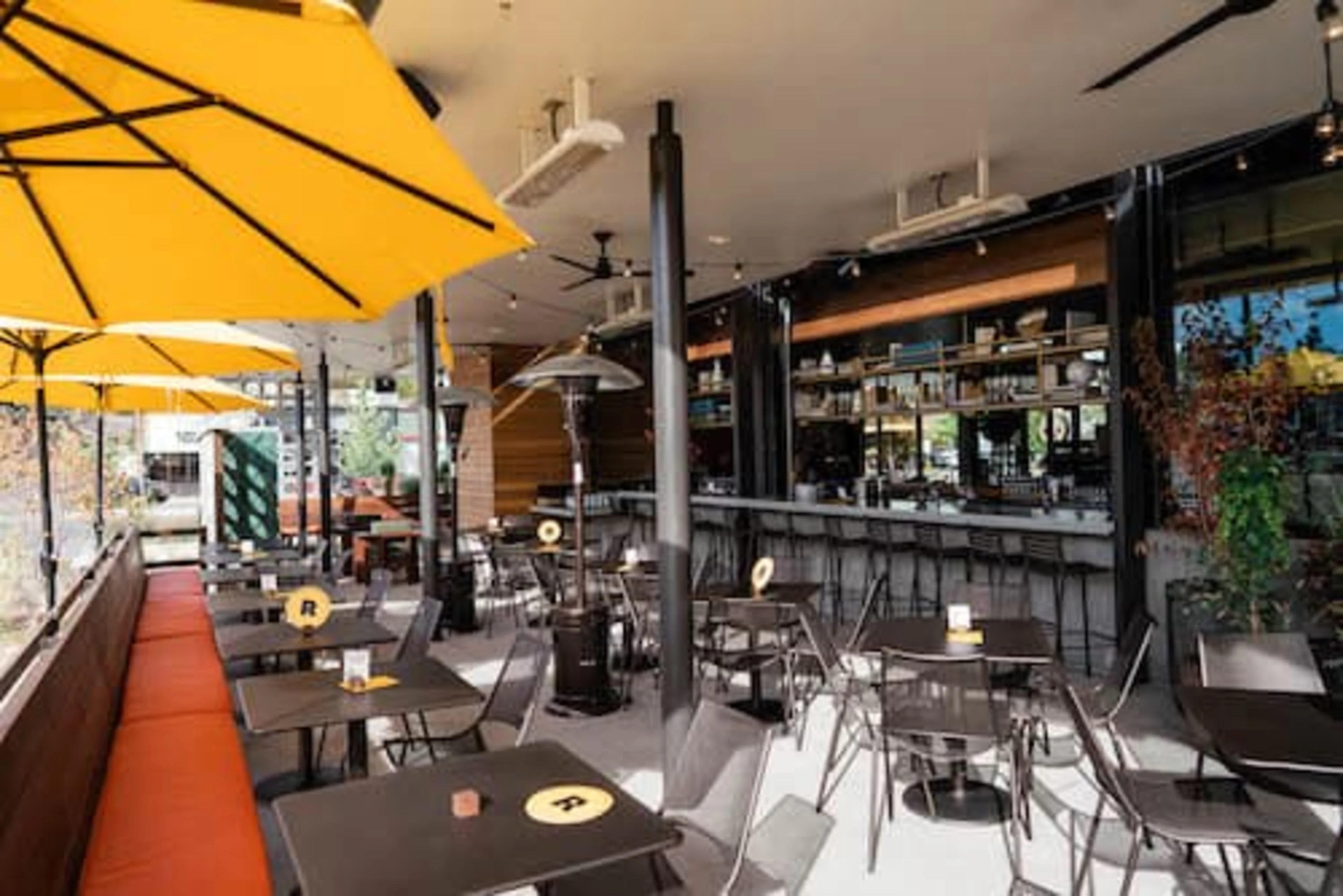 A patio with yellow umbrellas and a long red booth.