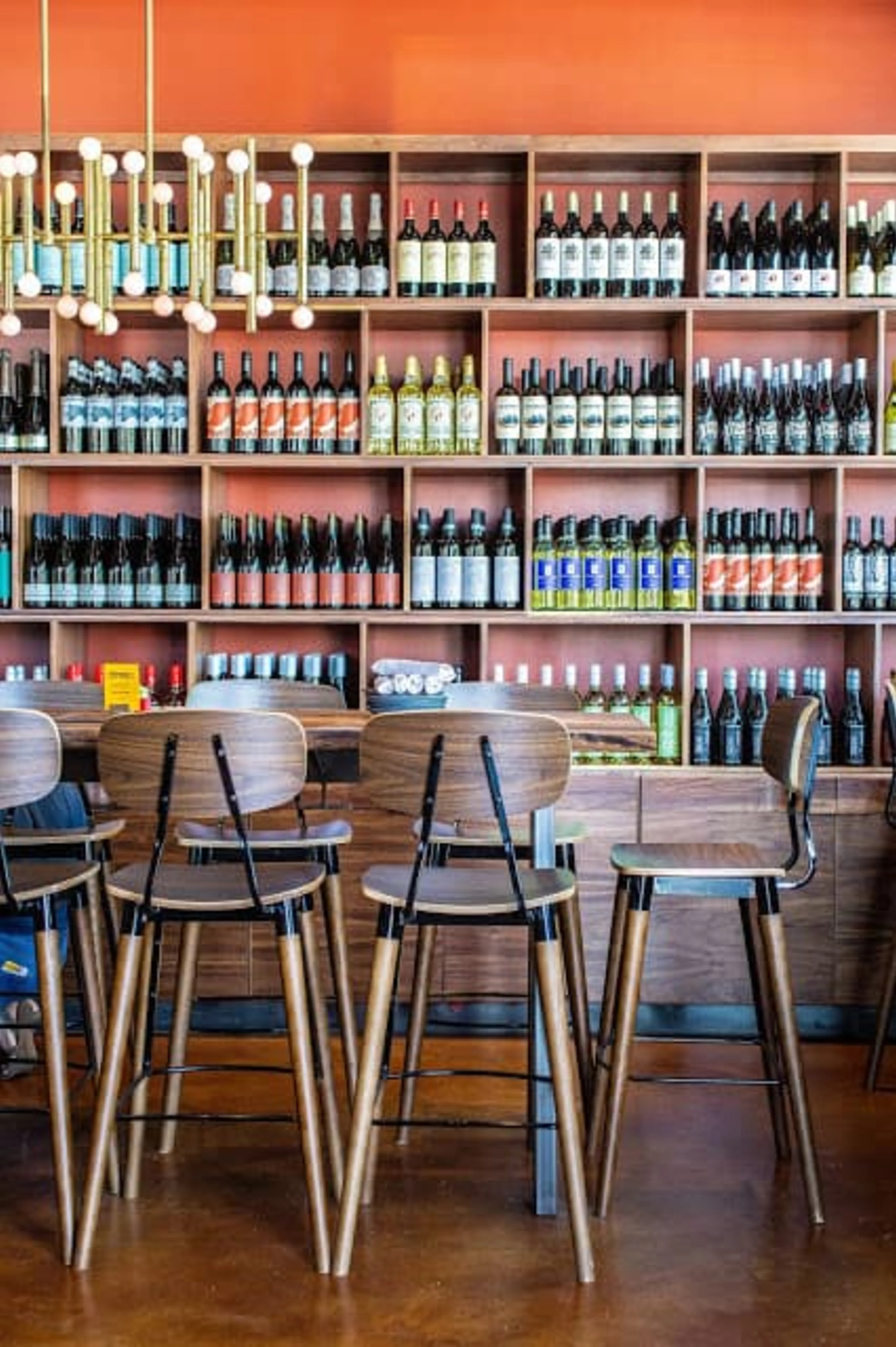 A wall of wine with a wooden table and chairs in front
