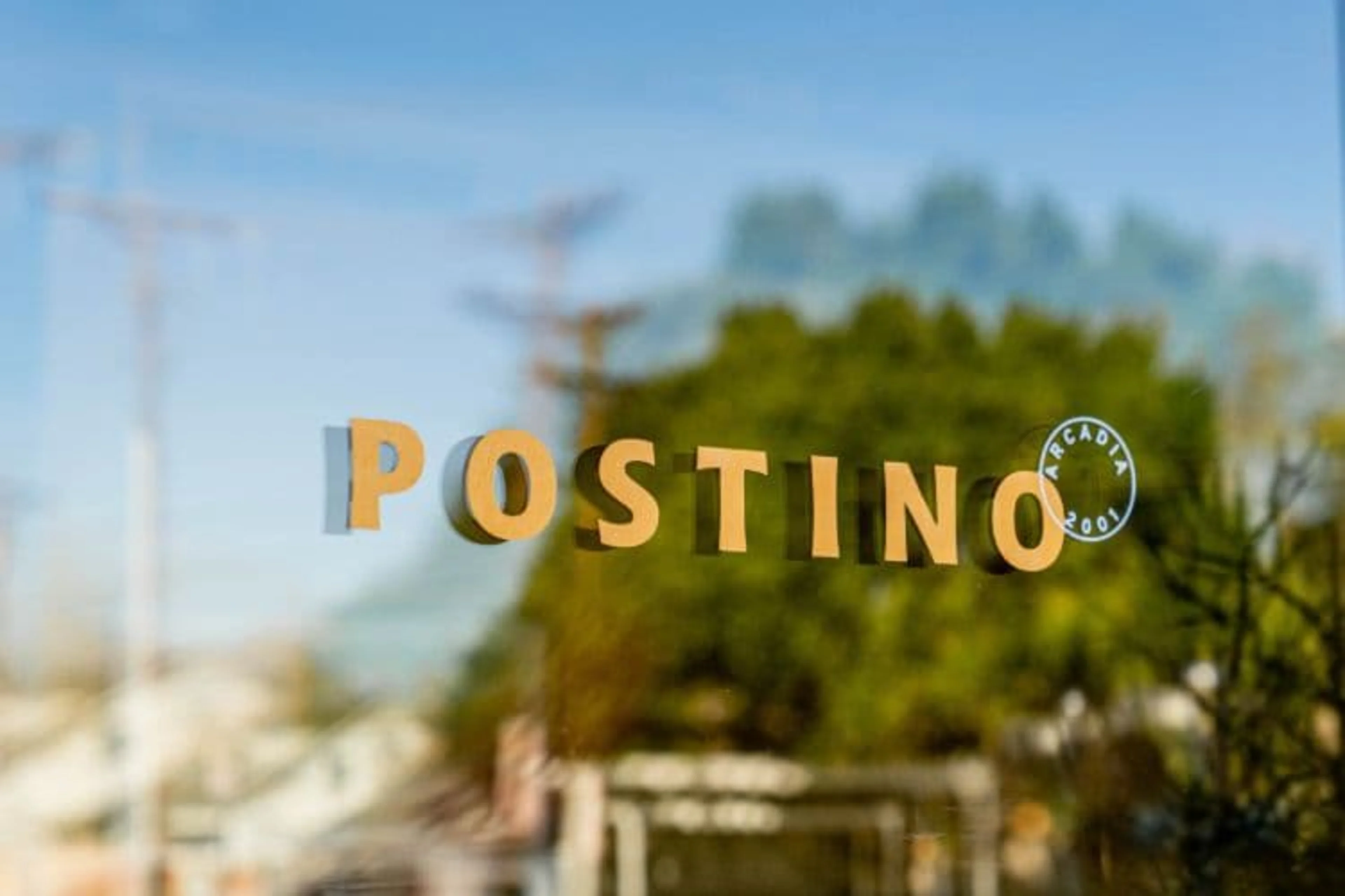 A glass door with a yellow Postino logo on it.