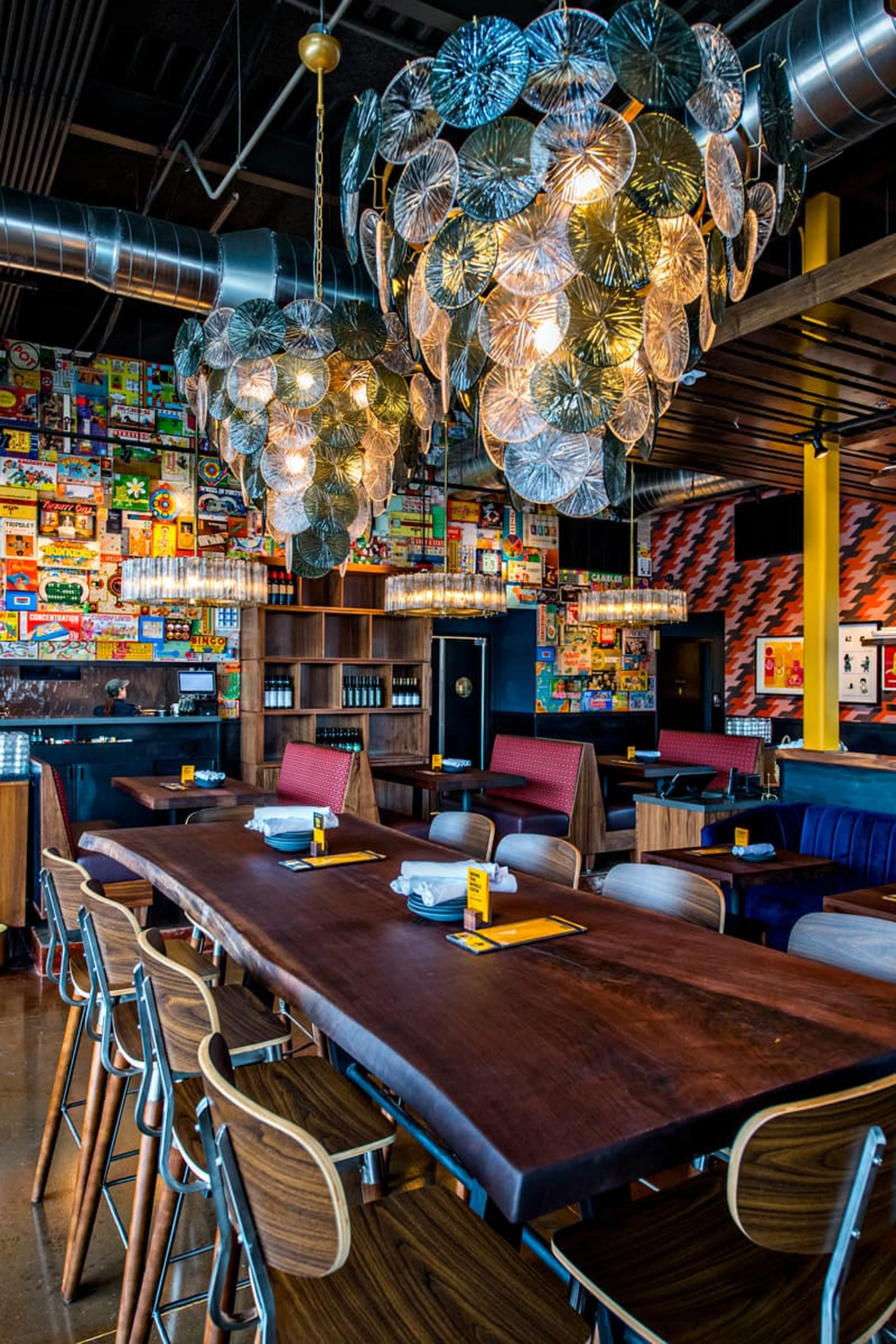 High-top wooden table with large chandeliers over it.