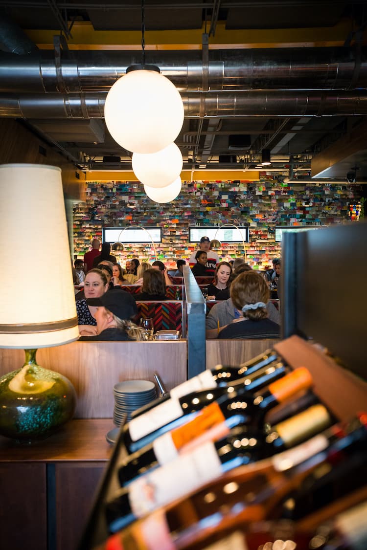 A row of wine bottles under glass orb lights.