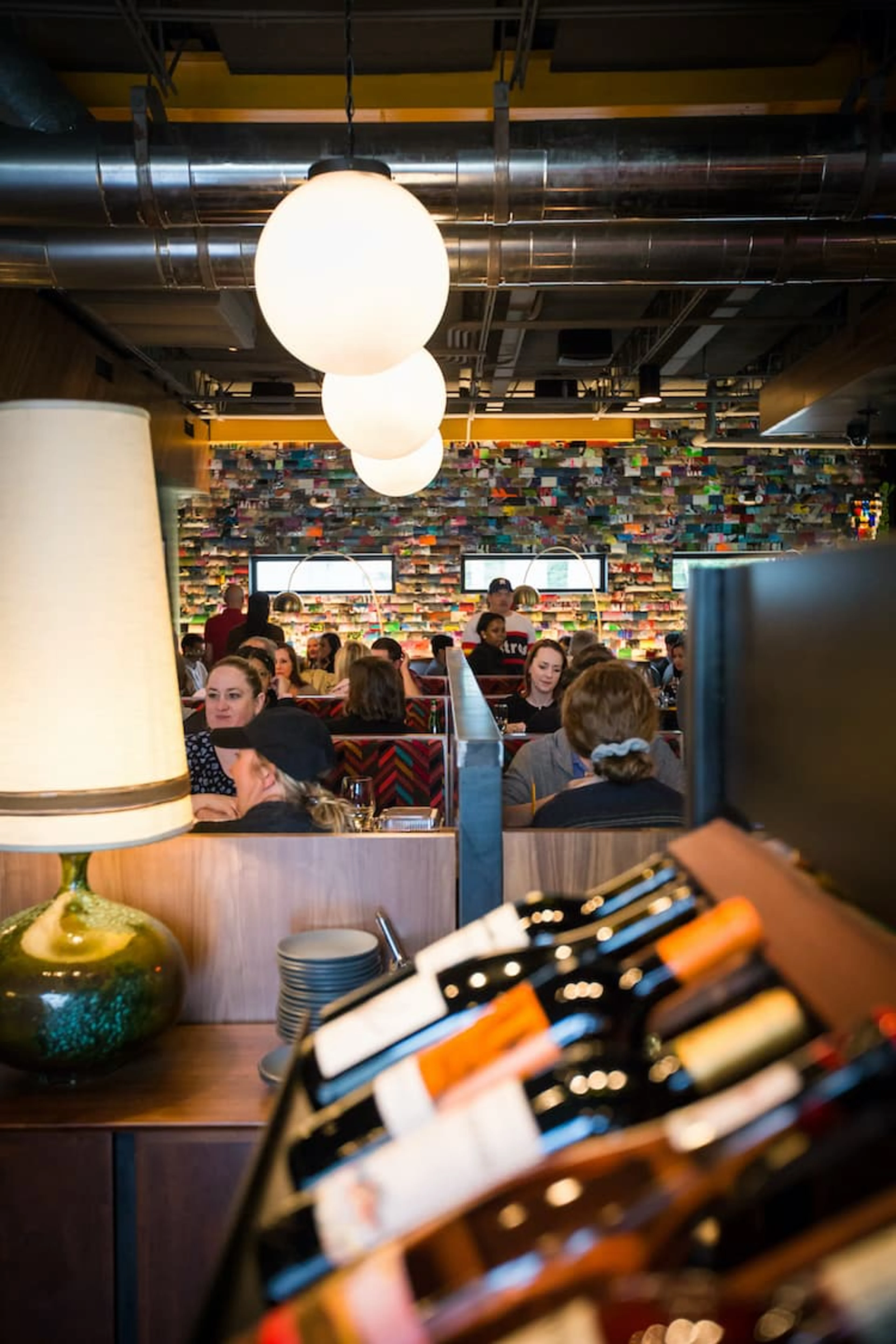 A row of wine bottles under glass orb lights.