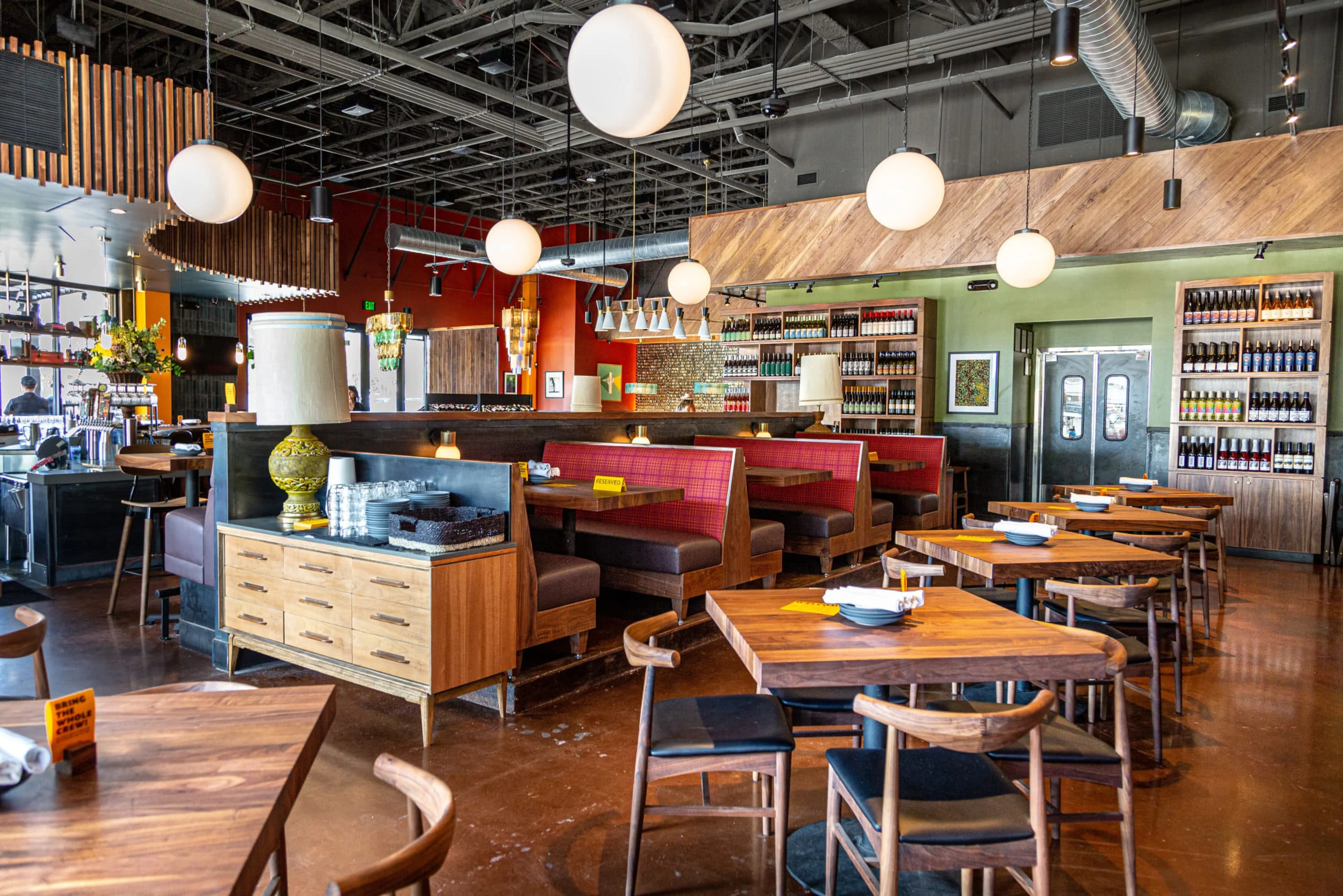 A restaurant with red booths and wooden tables and chairs.