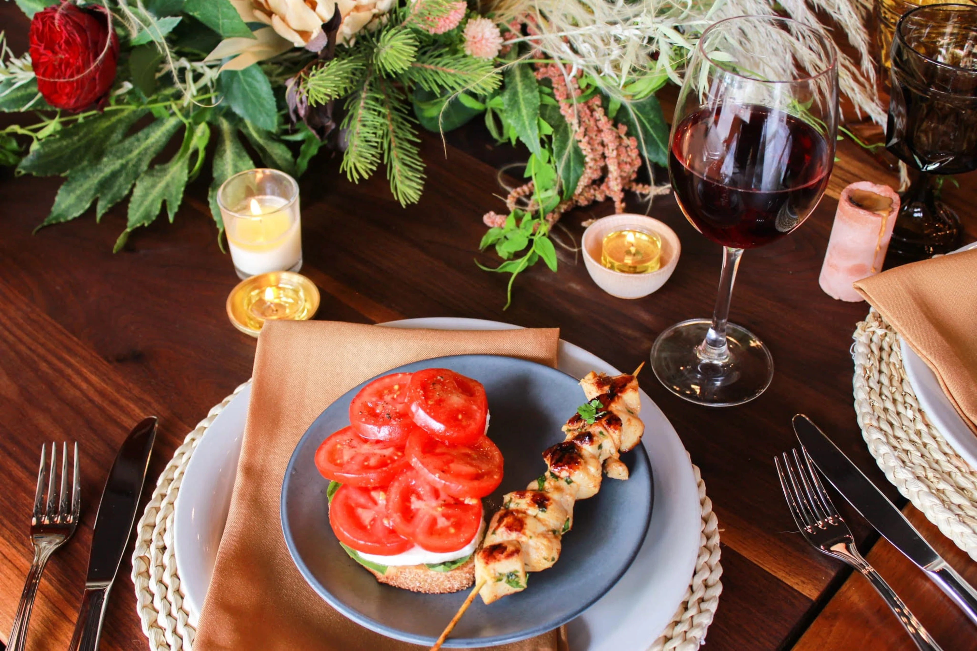 A wooden table set with a plate of bruschetta and a glass of red wine