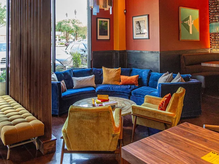 A room with red walls, a blue sofa, yellow chairs, and a large glass chandelier.