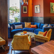 A room with red walls, a blue sofa, yellow chairs, and a large glass chandelier.