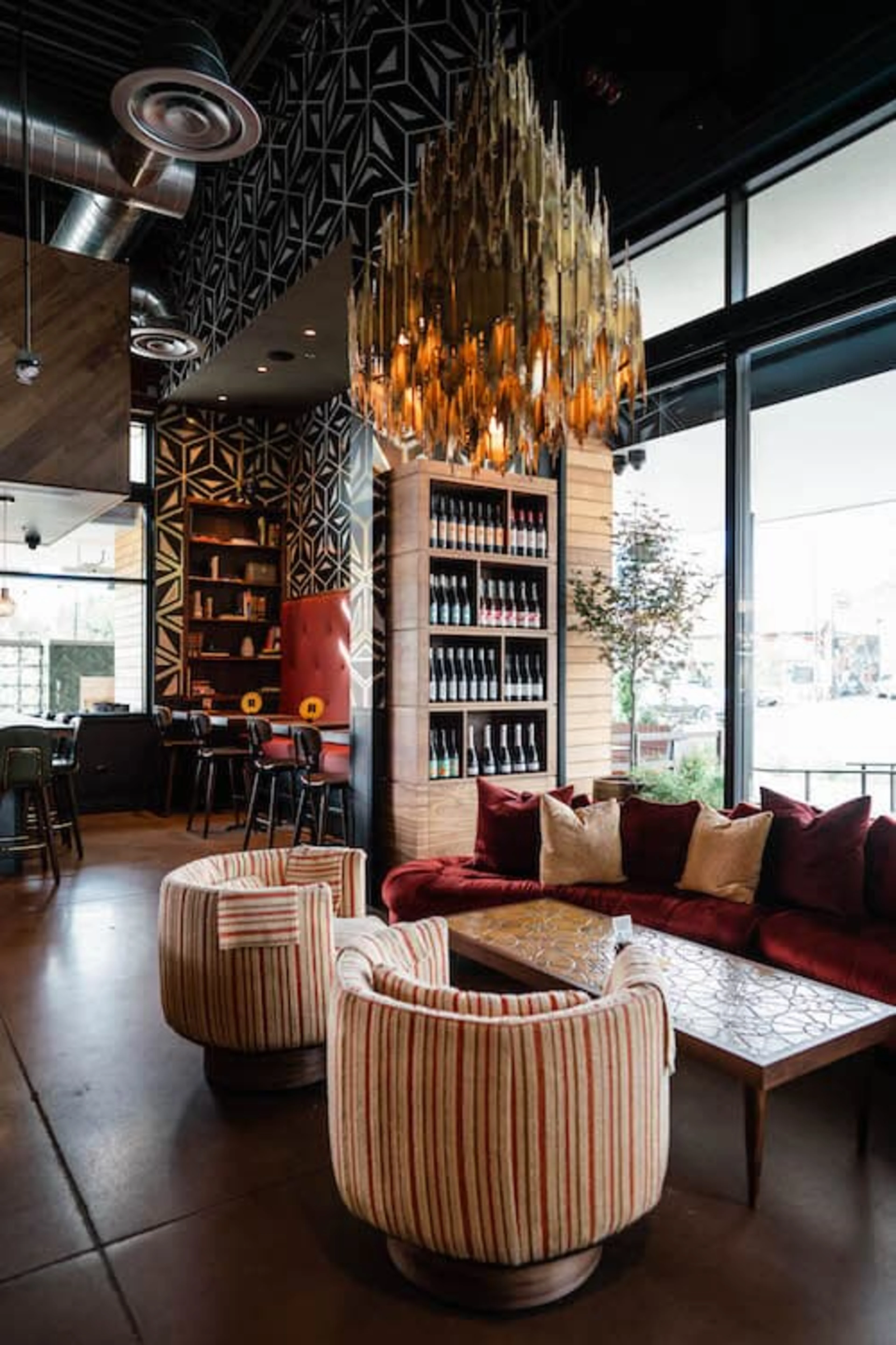 An empty restaurant with red and white chairs and a colorful glass chandelier. 