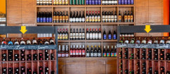 Shelves of wine on a wall with two wine displays in front of it.