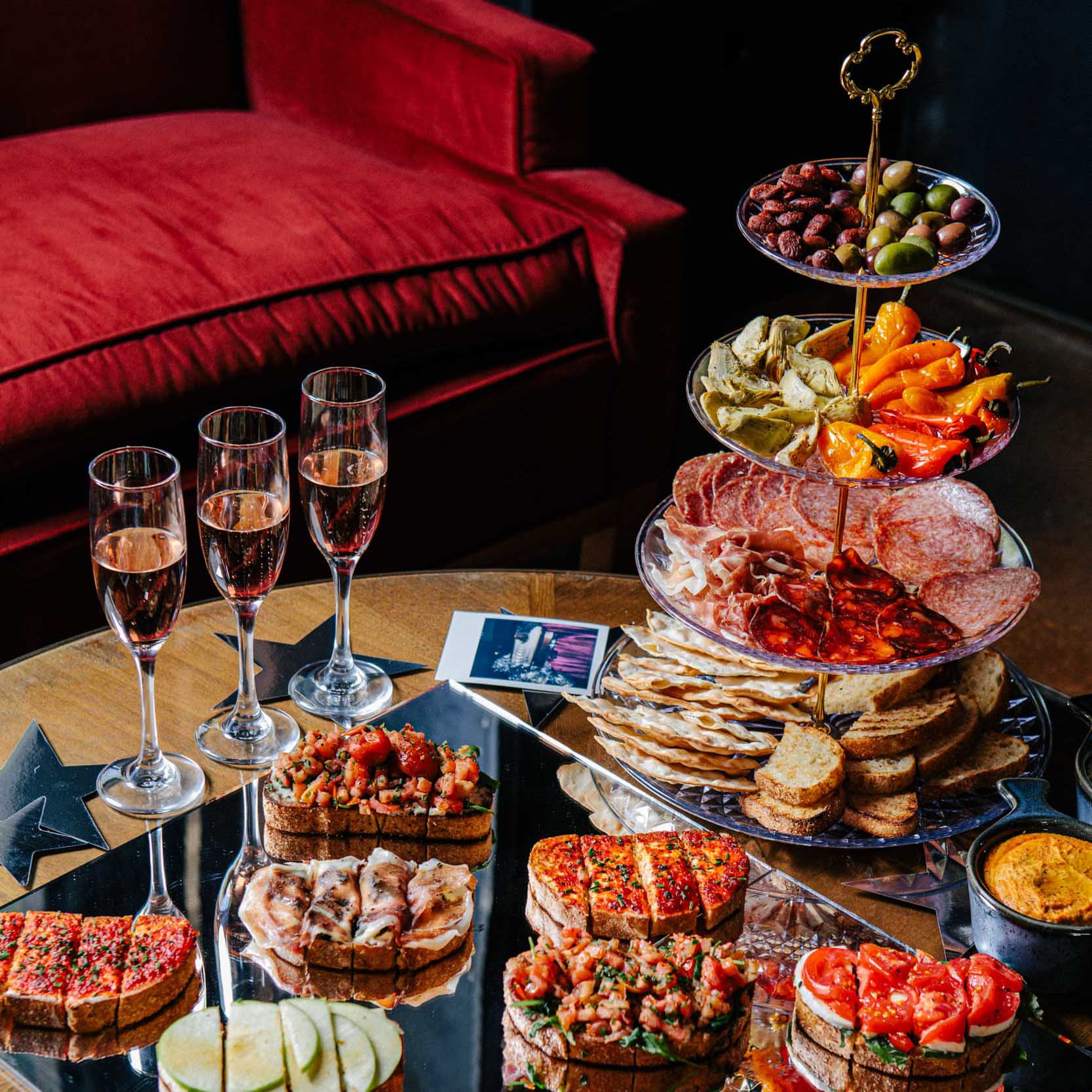 A large amount of bruschetta, cheeses, olives, and charcuterie meats in a spread on a table.