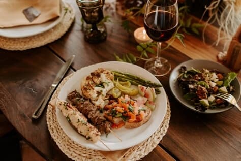 A wooden table covered with plates and a glass of wine.