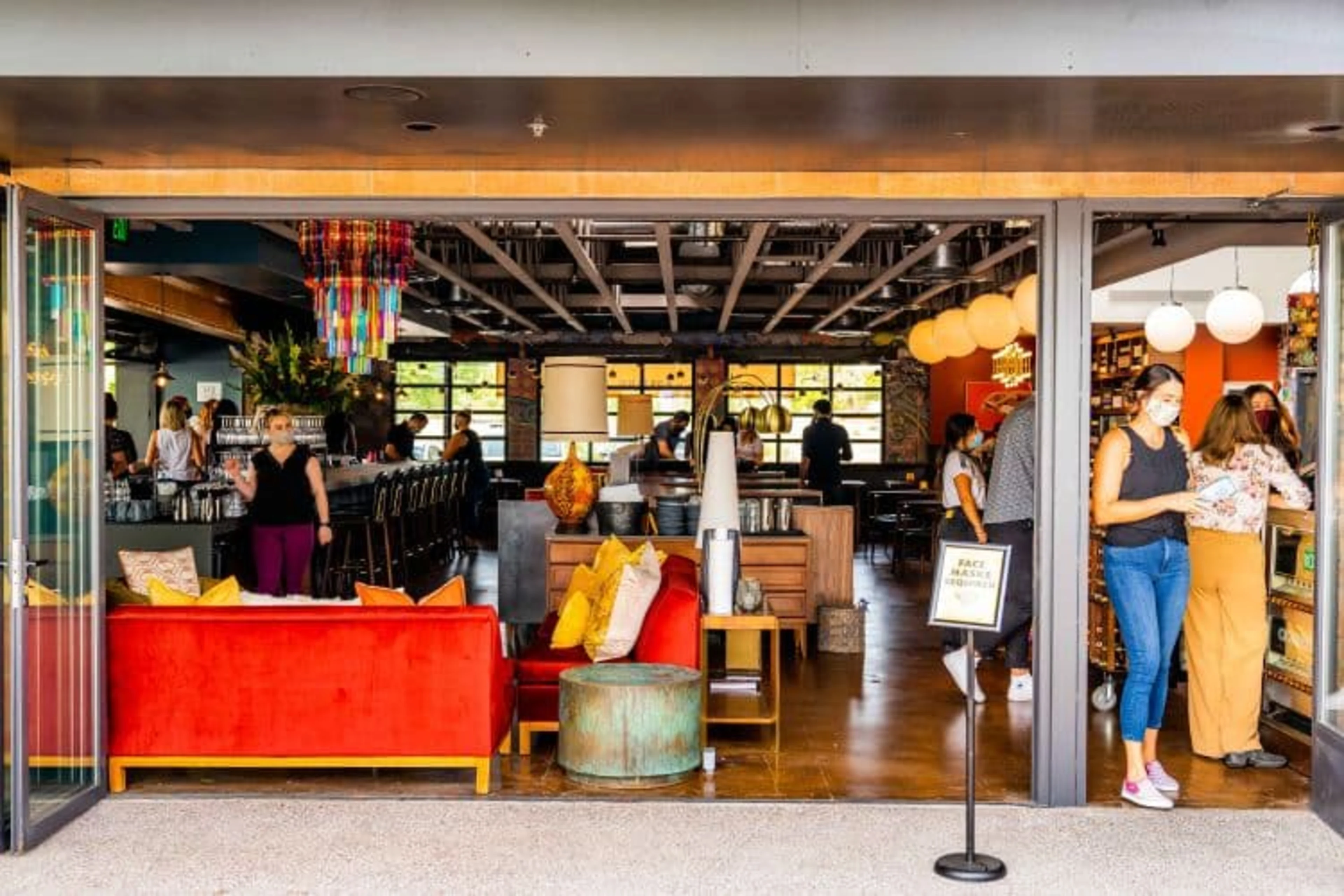 A busy restaurant with a long bar and a red sofa.