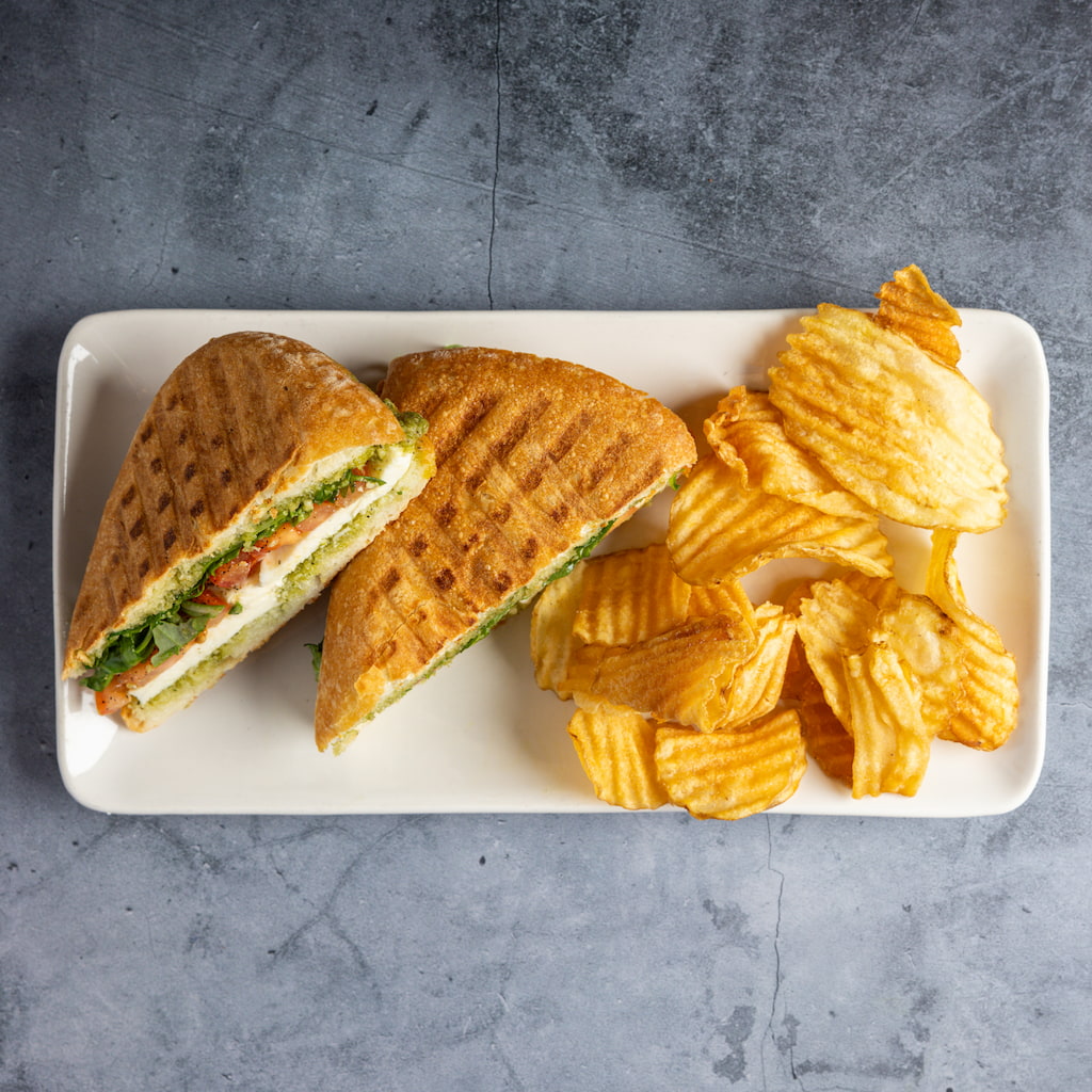 Caprese Panini with basil pesto, fresh mozzarella, roma tomato, arugula, balsamic, olive oil.