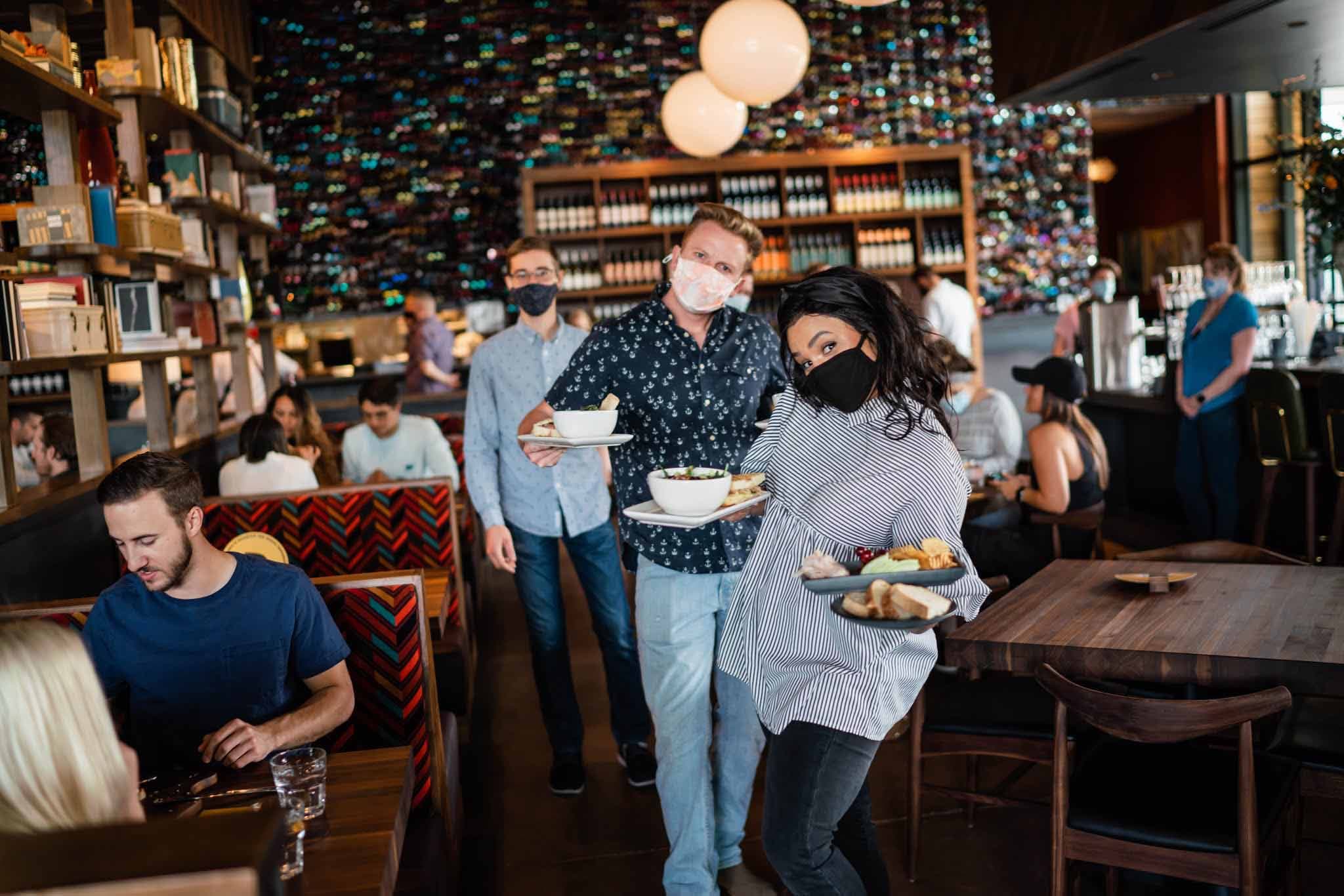 Servers holding up trays of food and posing