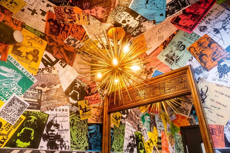 A unique starburst light surrounded by colorful posters and a large mirror.