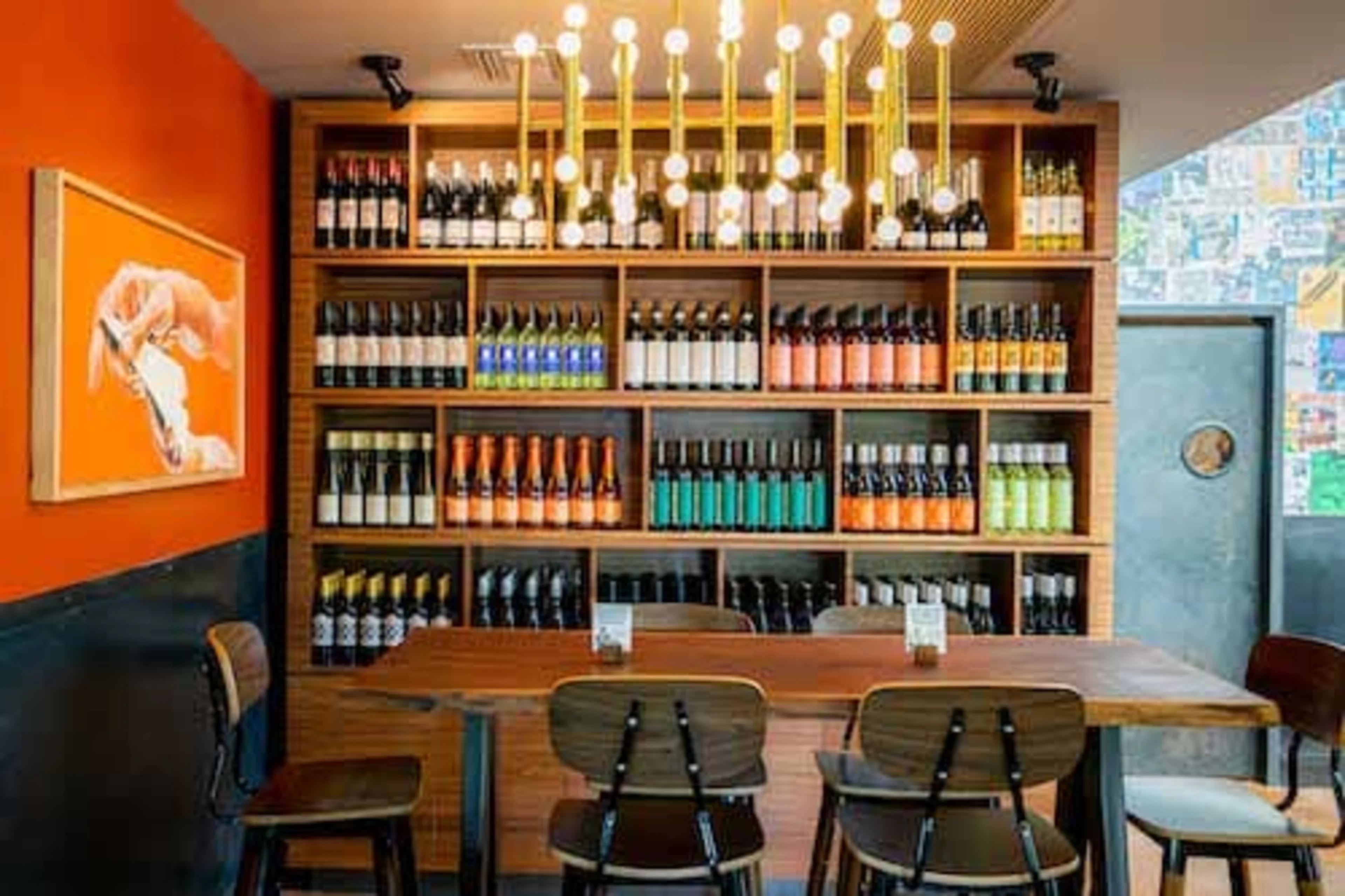 A wooden table with chairs and a bookcase full of wine.
