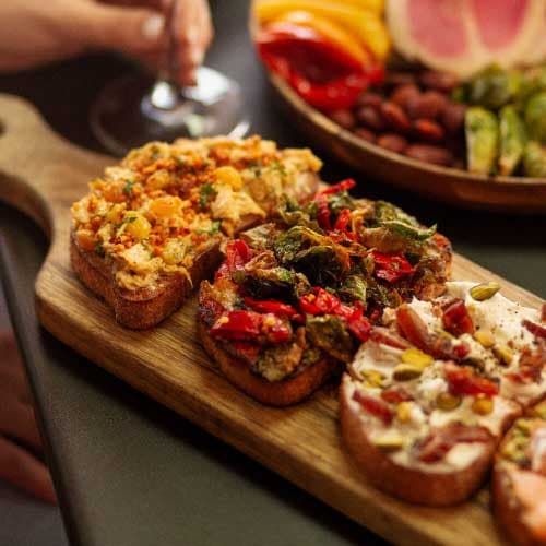 A wooden board full of bruschetta. 